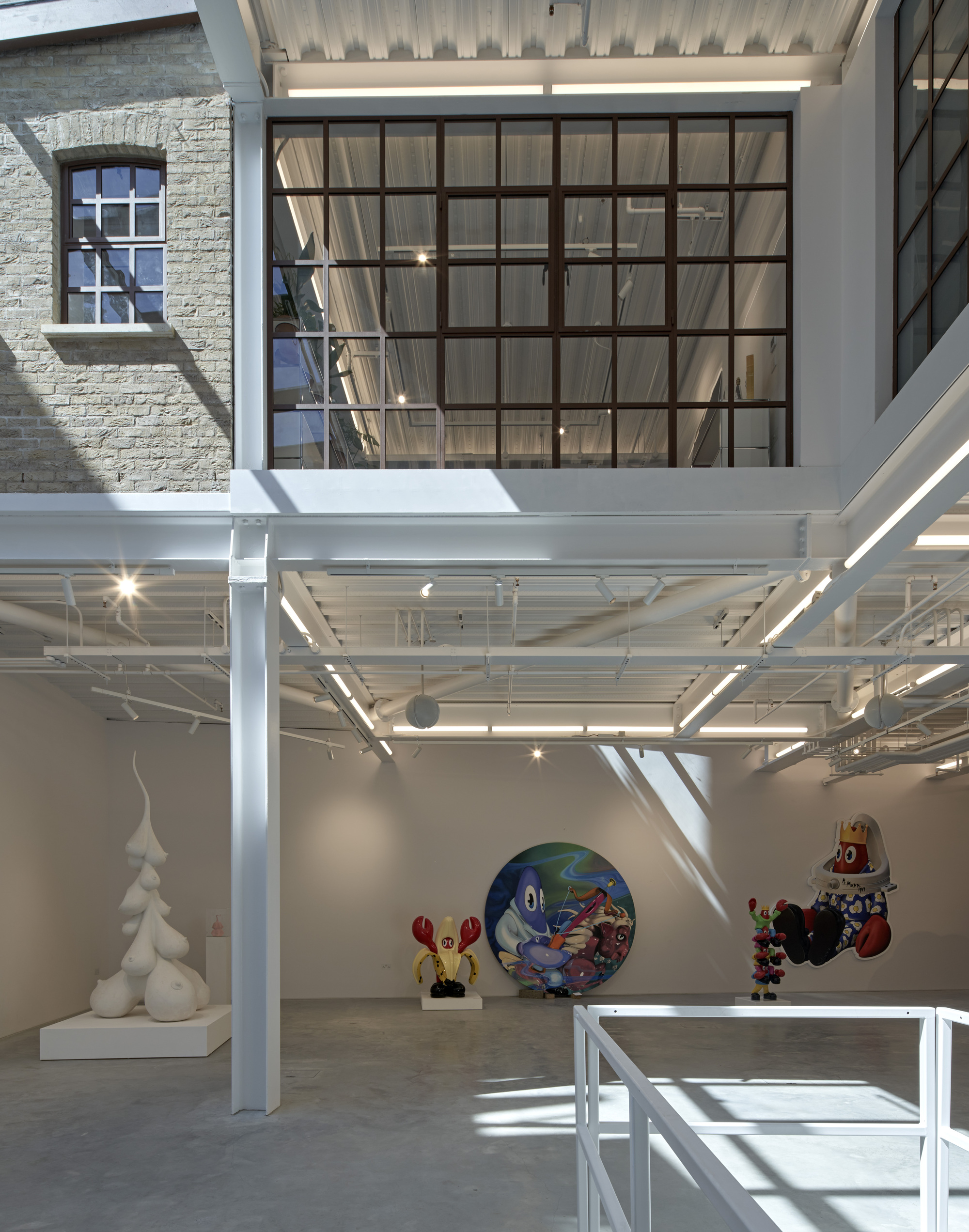 Large steel-framed clerestory window above white structural columns bringing daylight into the gallery space