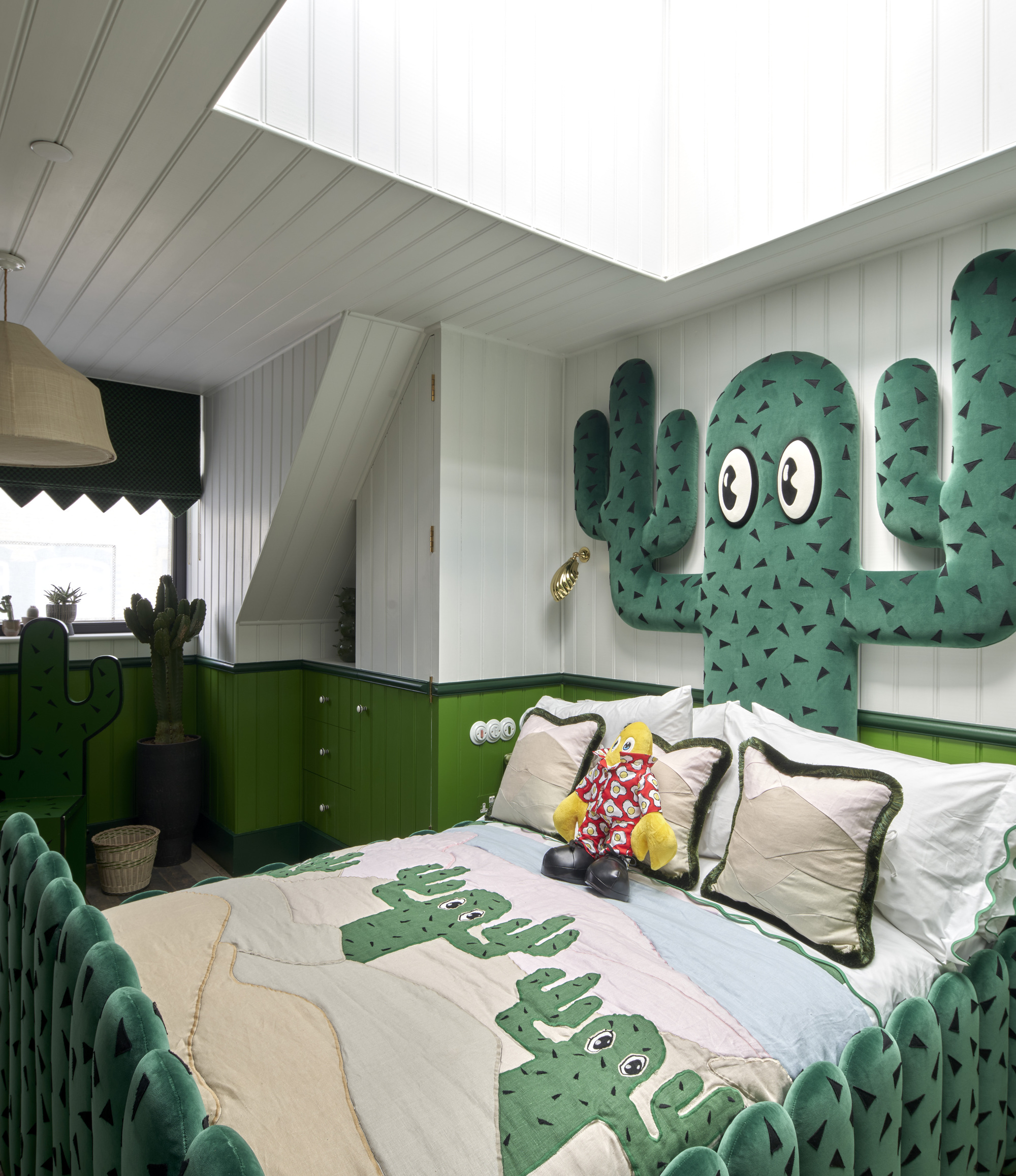 Bedroom with green cabinetry and cactus-themed wall decoration beneath white paneled ceiling