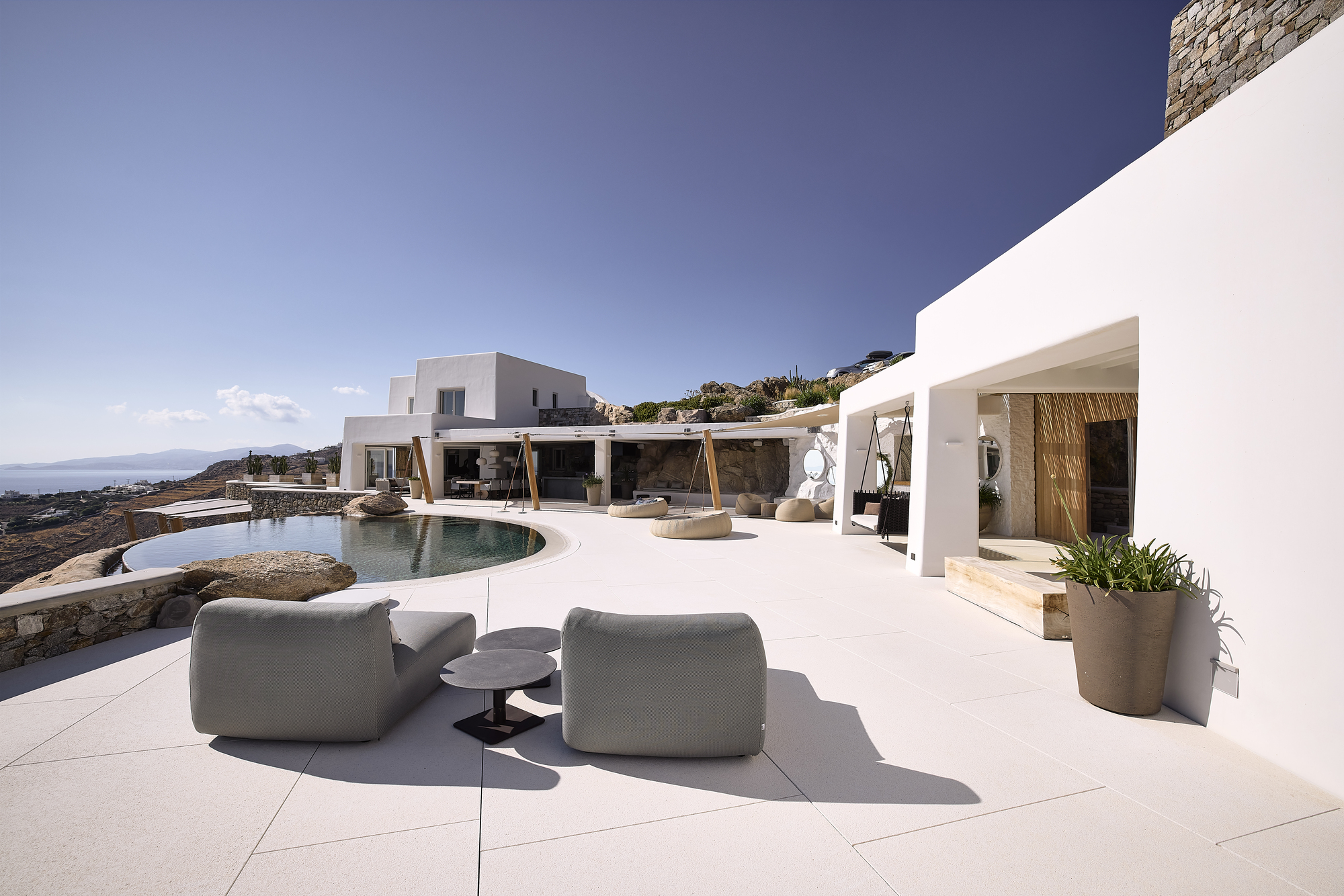 White terrace with curved pool and timber pergola overlooking the ocean