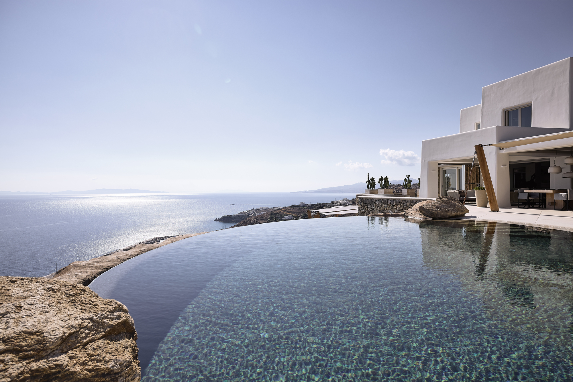 Infinity pool merging with the sea horizon framed by natural rock formations under clear sky