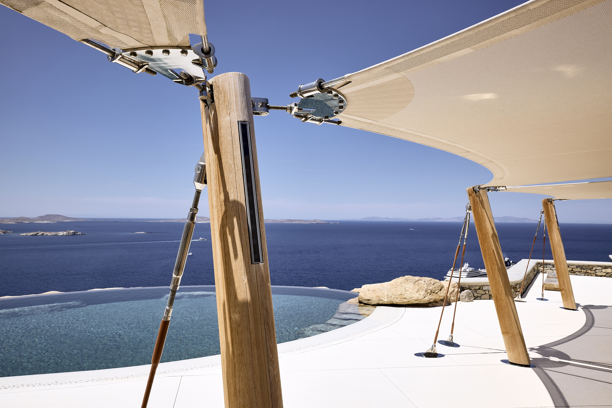 Detail of timber mast and tensile fabric structure with metal fittings above the infinity pool