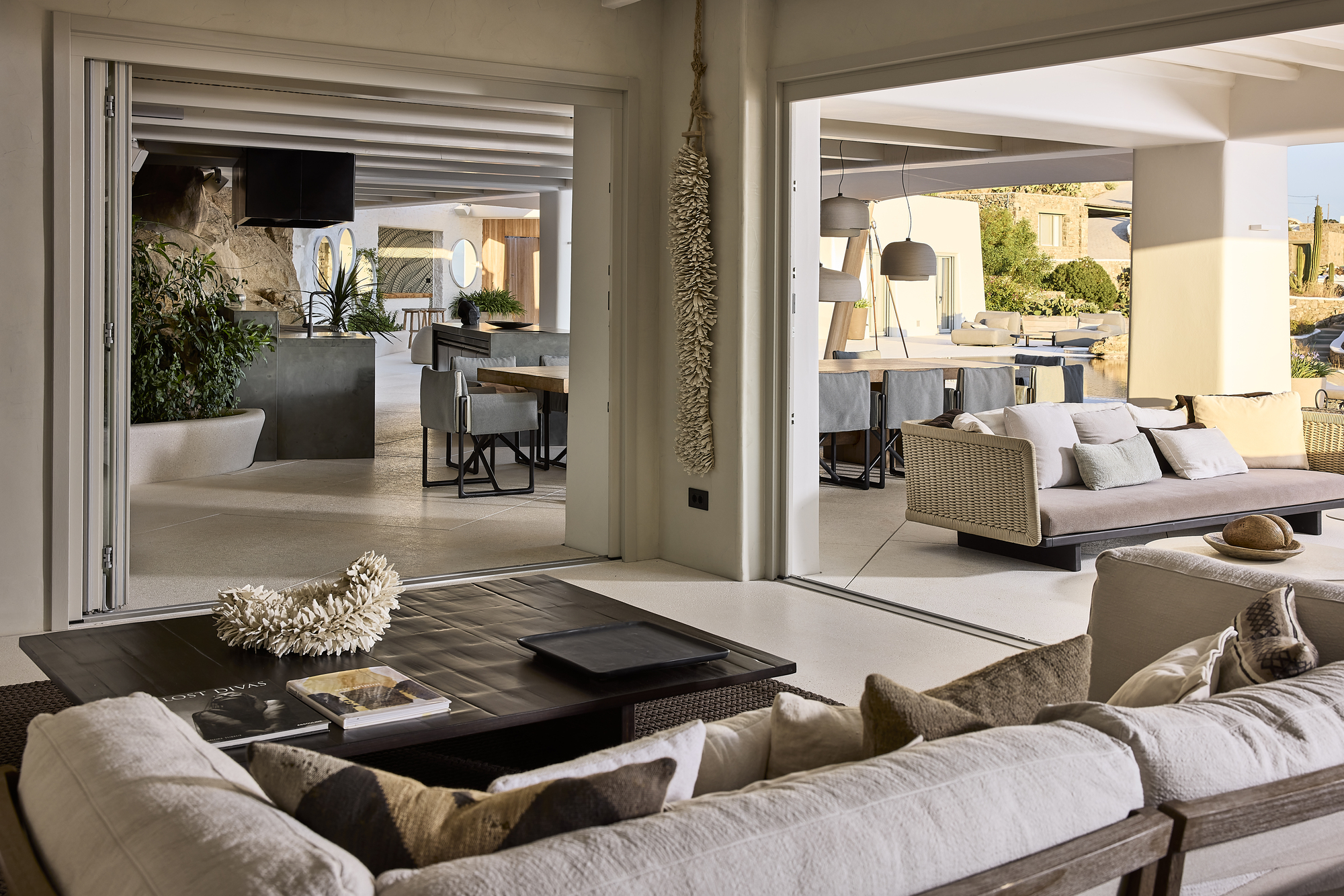 Interior courtyard view through folding glass doors connecting multiple seating areas in daylight