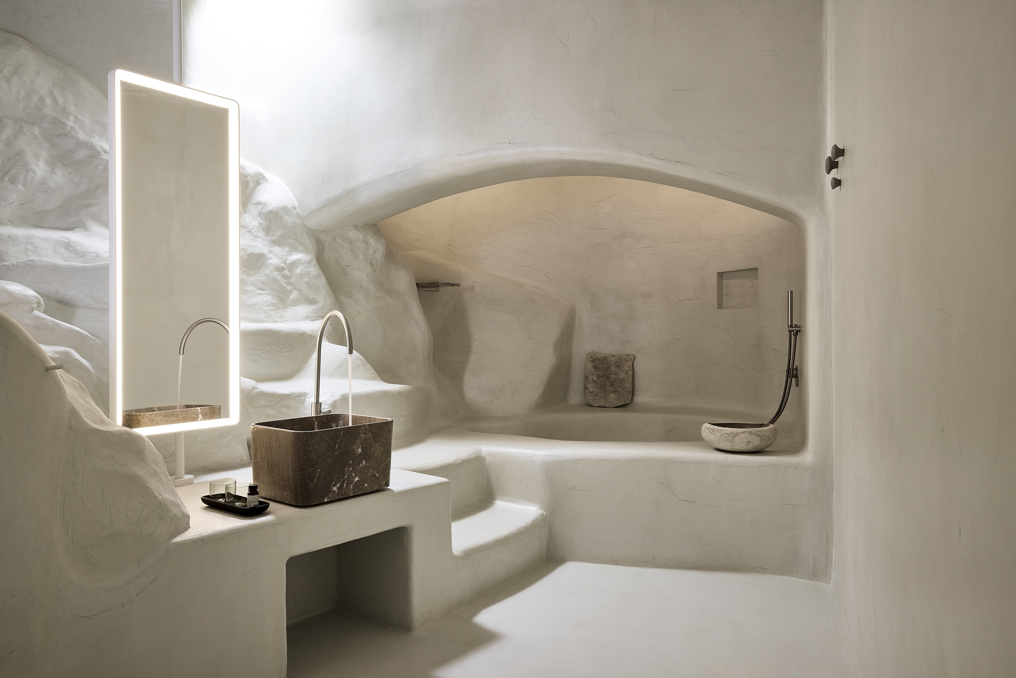 Vaulted bathroom grotto with plastered walls and stone sink alcove casting soft shadows