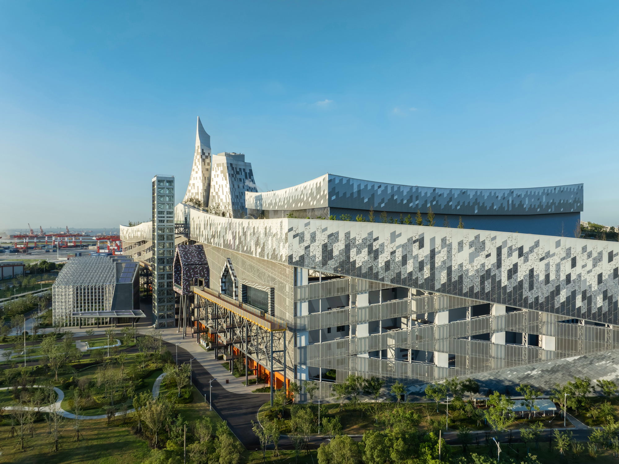 Aerial view of the patterned metal panel facades and angular volumes rising above the landscaped park