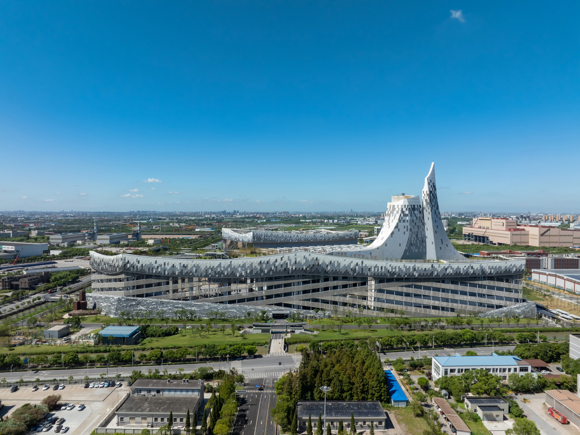 Distant view of the faceted white tower and undulating roof spanning the horizontal base structure