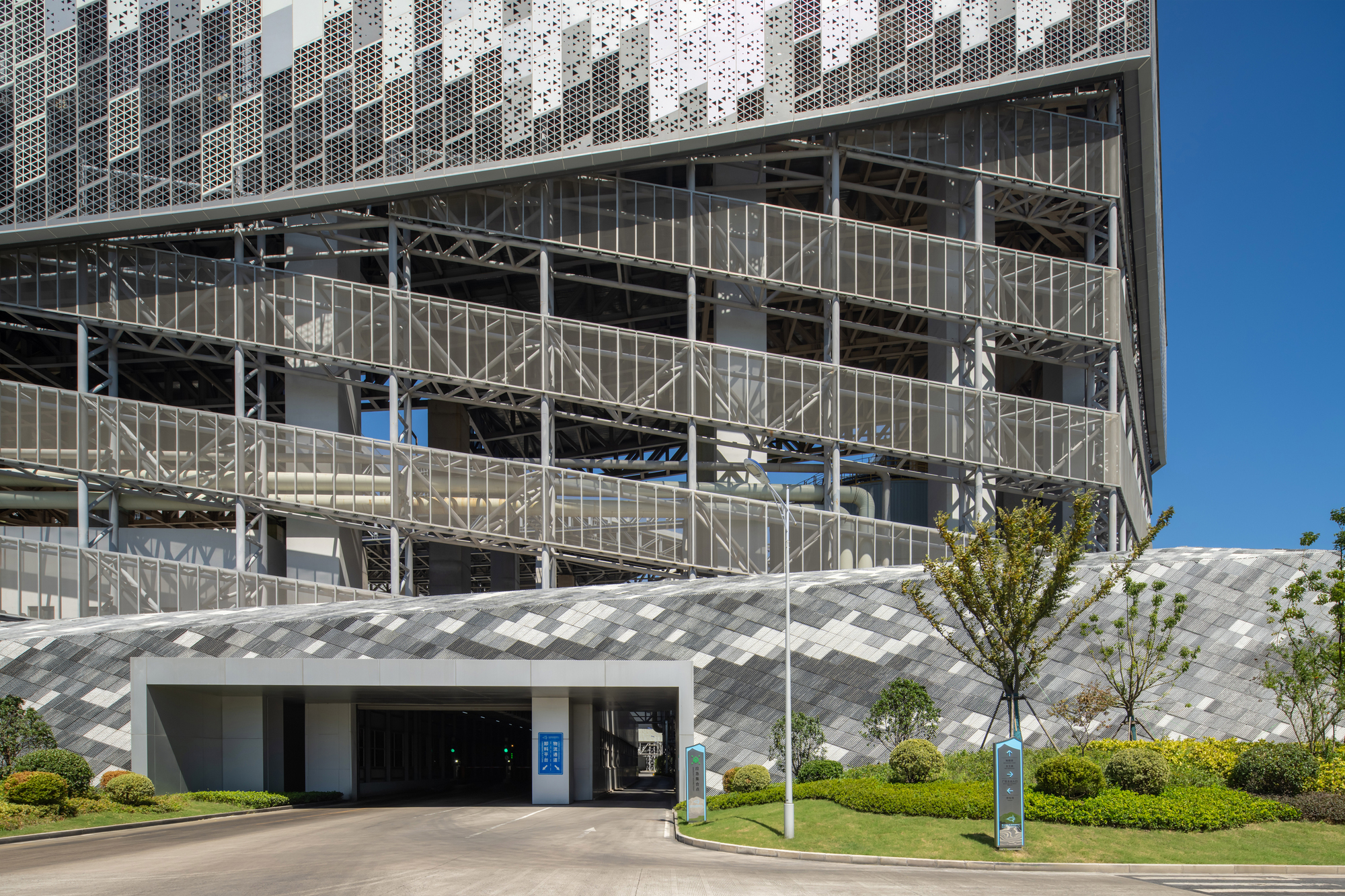 Entry canopy with chevron-patterned soffit beneath the glass and steel tower podium and lawn