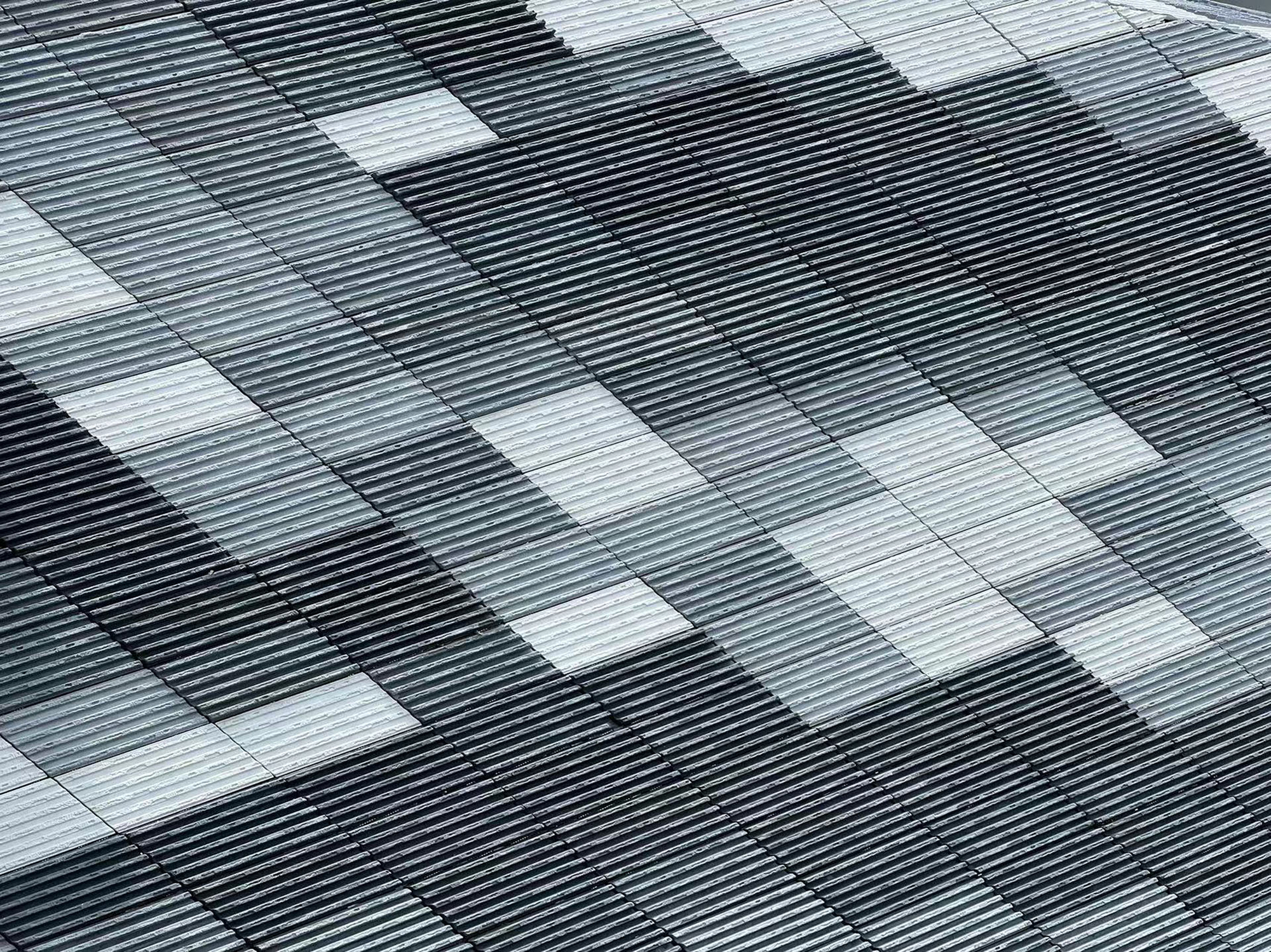 Detail of the horizontal metal louvered facade with scattered white panel openings in a pixelated pattern