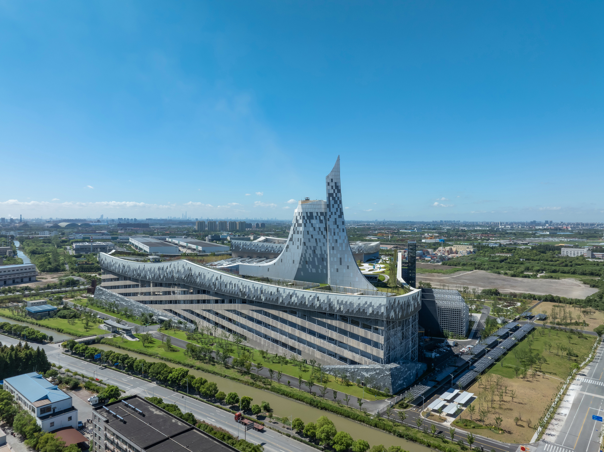 Aerial view of the triangular volume rising above the patterned facade and surrounding industrial landscape