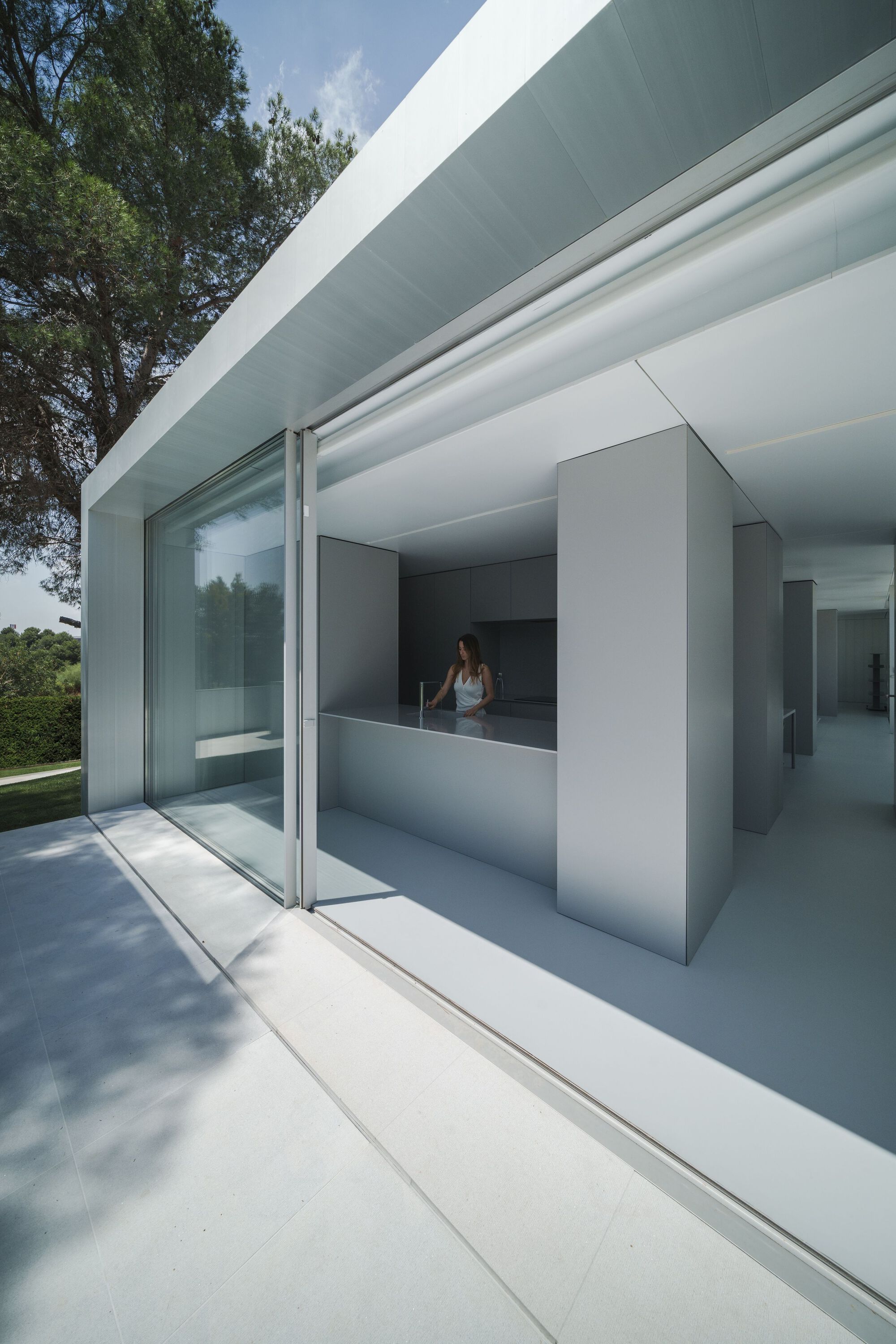 Glass corner threshold with sliding panels connecting interior kitchen volume to exterior terrace