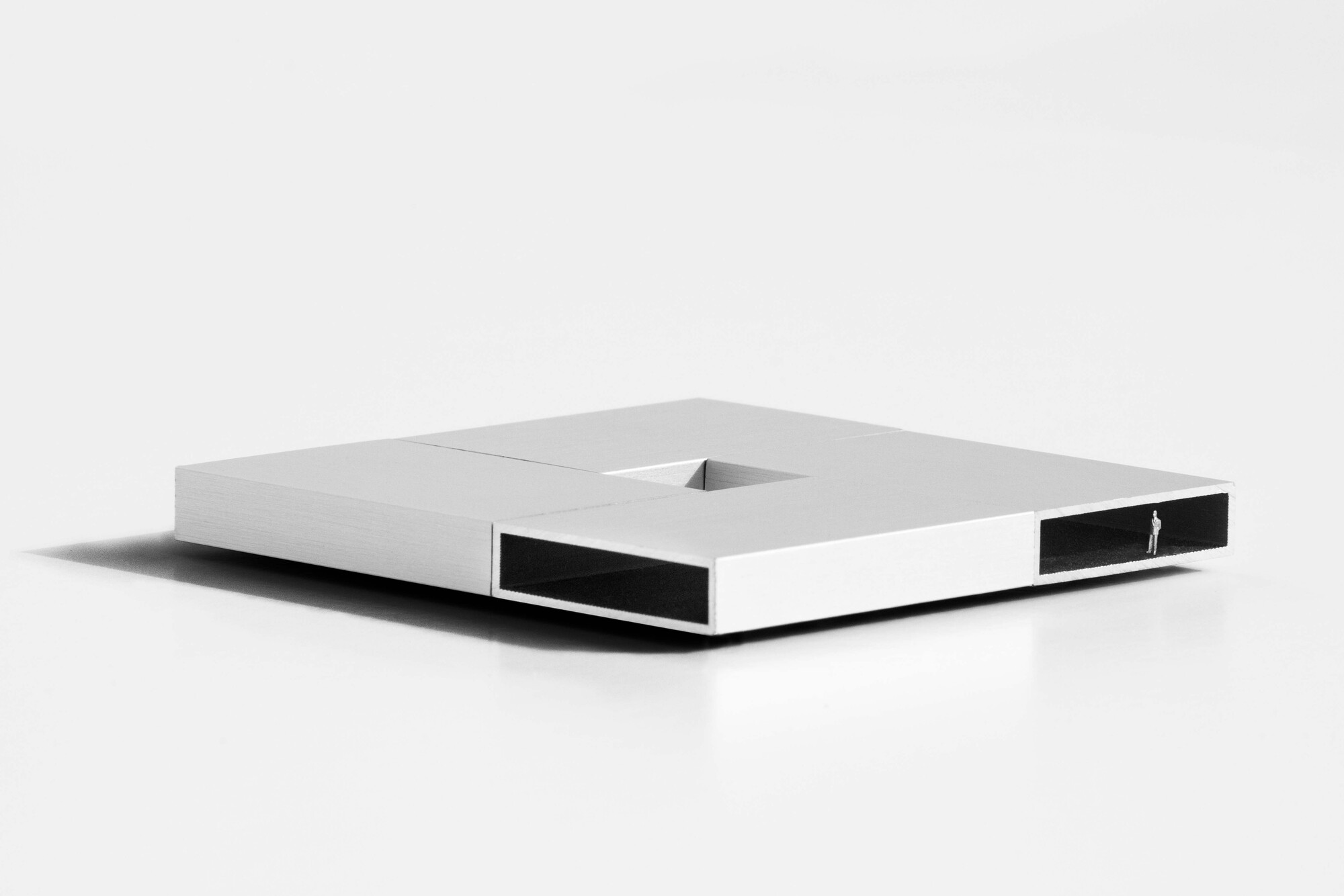 Architectural model with horizontal window slits and central rooftop aperture on white base