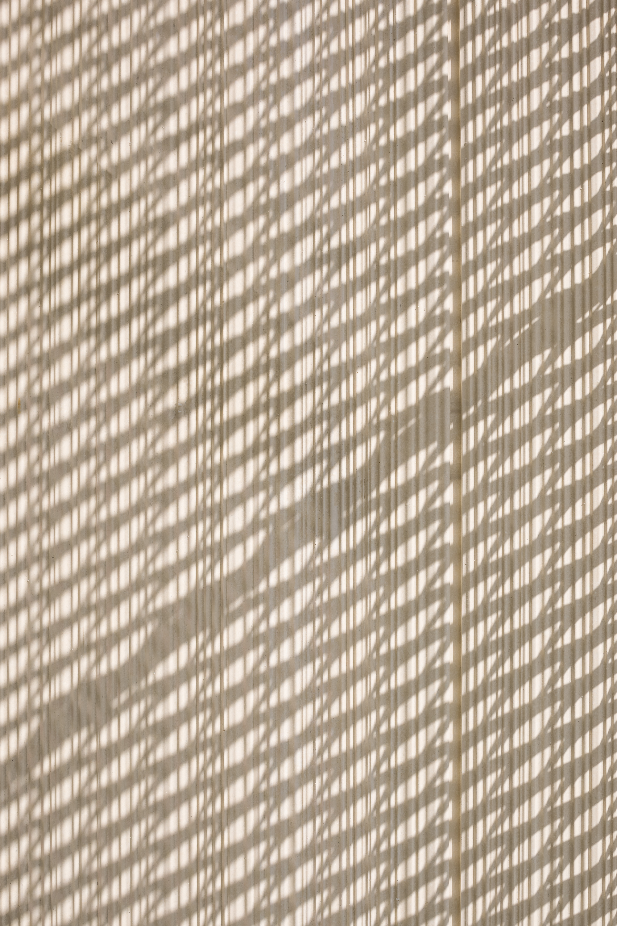 Dappled sunlight casting diagonal shadow patterns across a textured beige wall surface