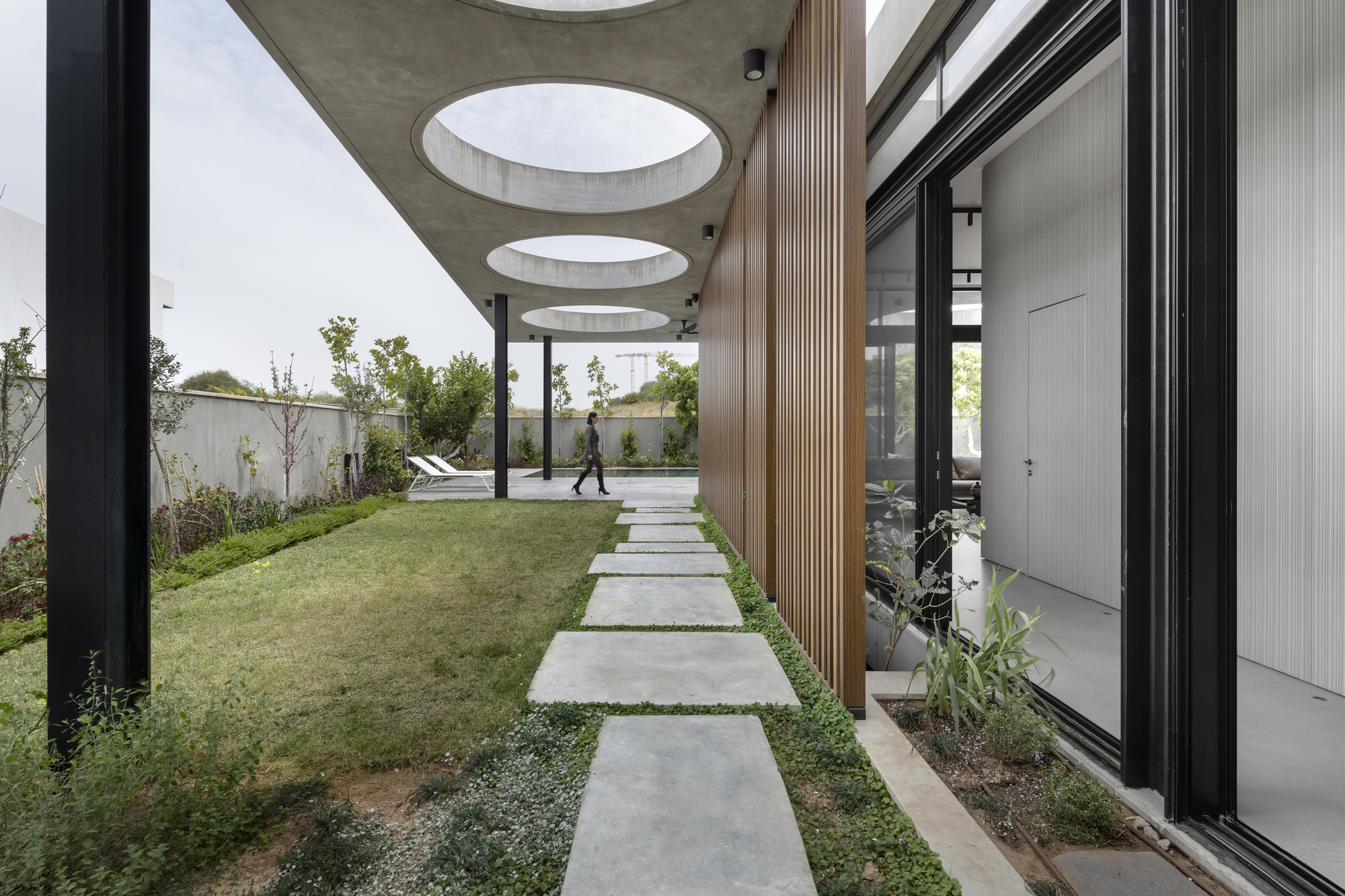 Concrete pathway with circular skylights cut into the canopy ceiling as a person walks through