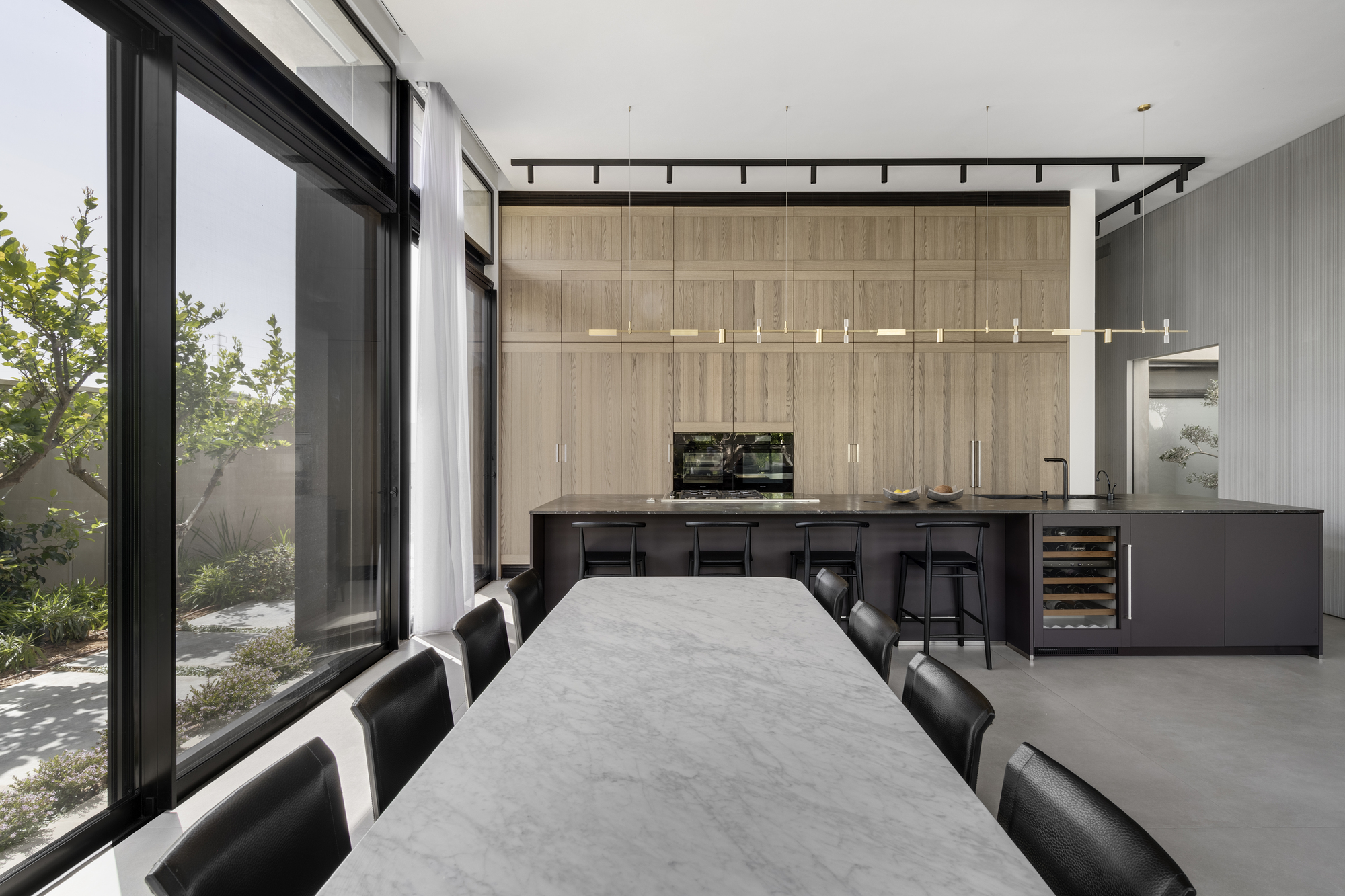 Open kitchen and dining area with floor-to-ceiling glazing overlooking a planted courtyard
