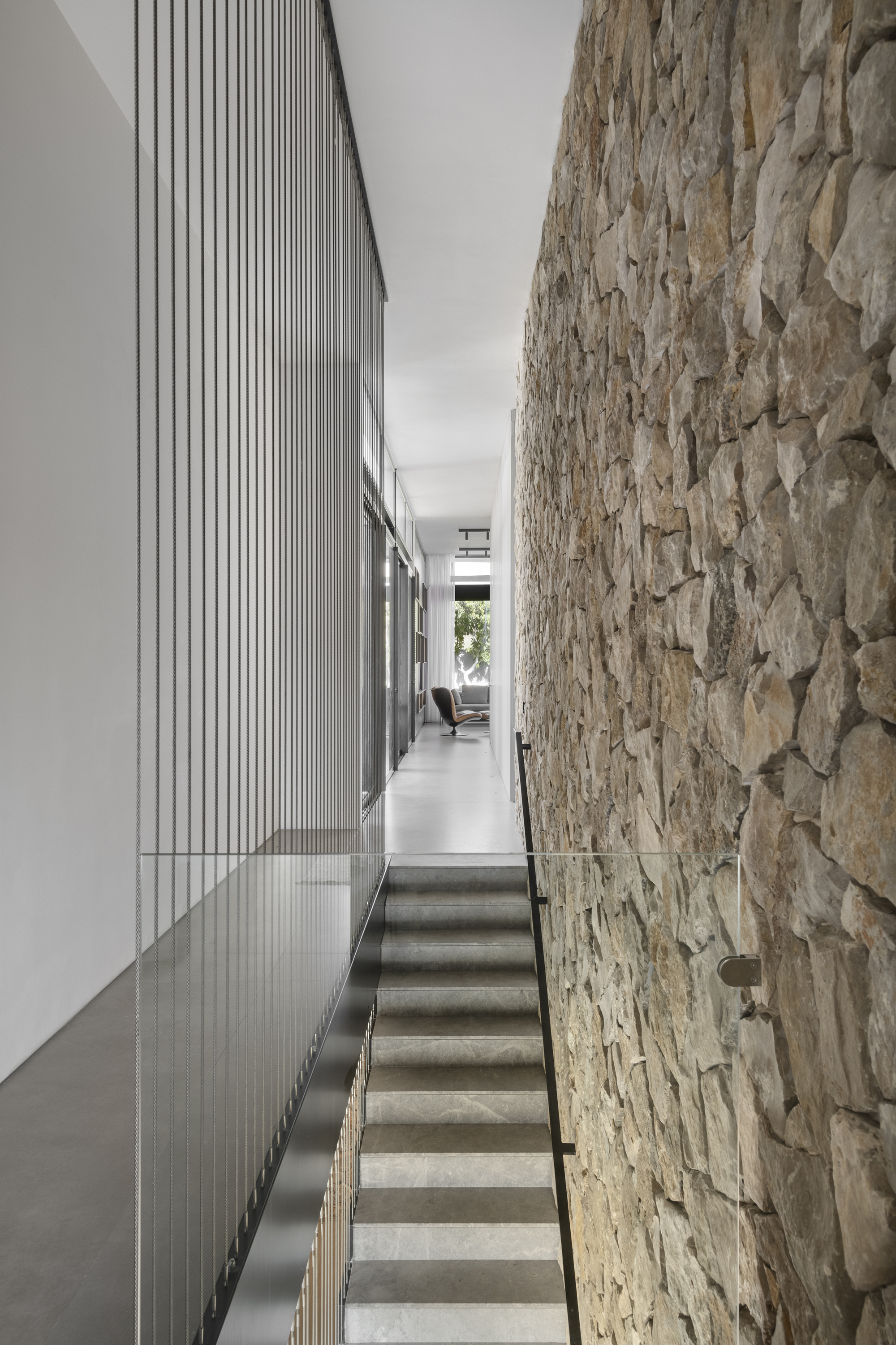 Concrete stairs flanked by a rough stone wall and vertical timber battens in natural light