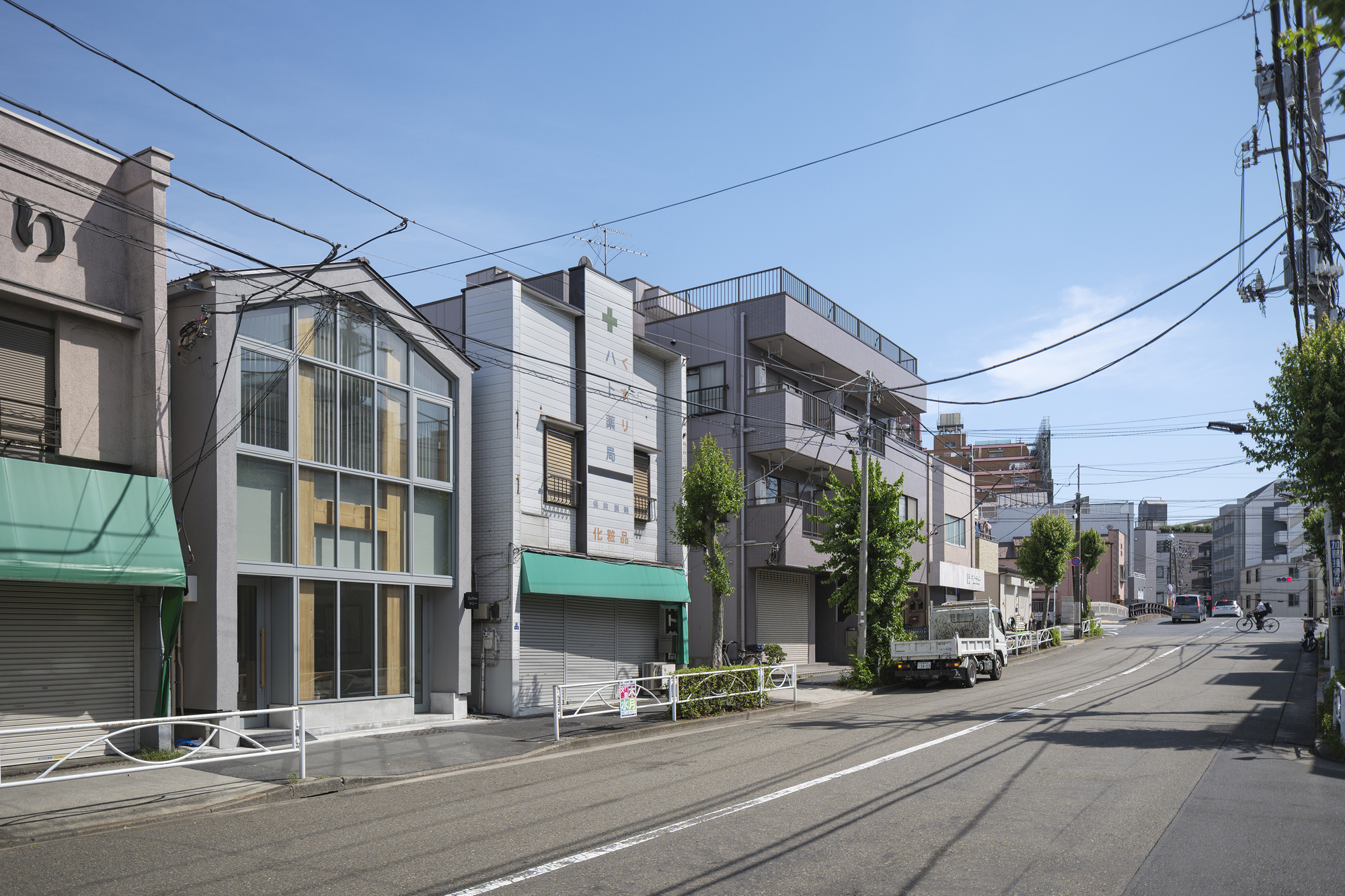 Perspective down the street showing the glazed facade among low-rise commercial and residential buildings