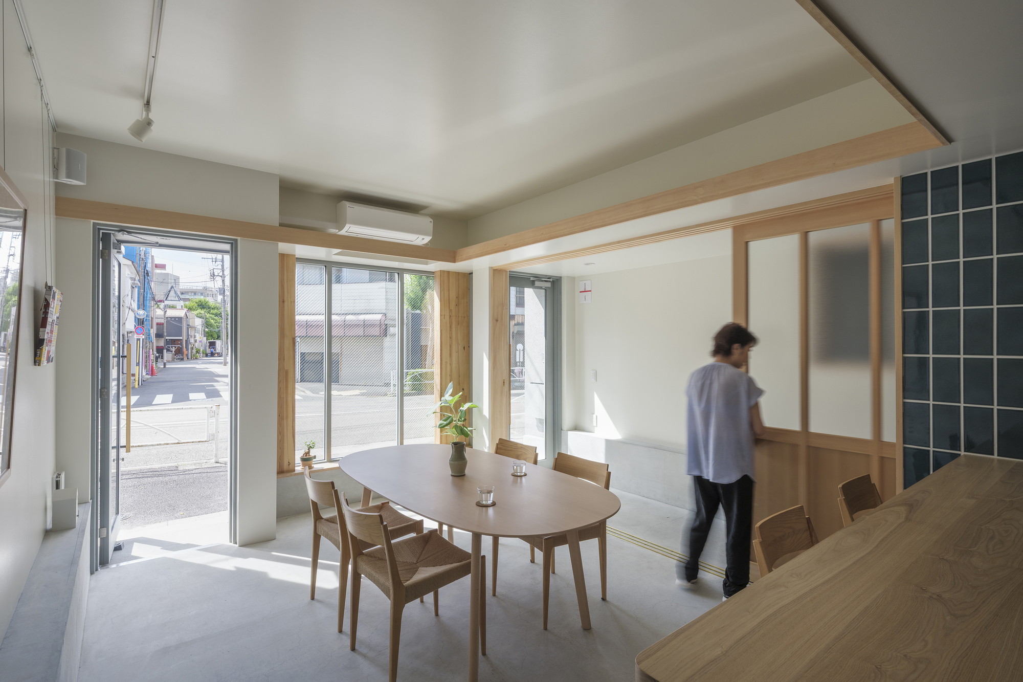 Ground floor dining area with timber table and translucent sliding screens as a resident walks past