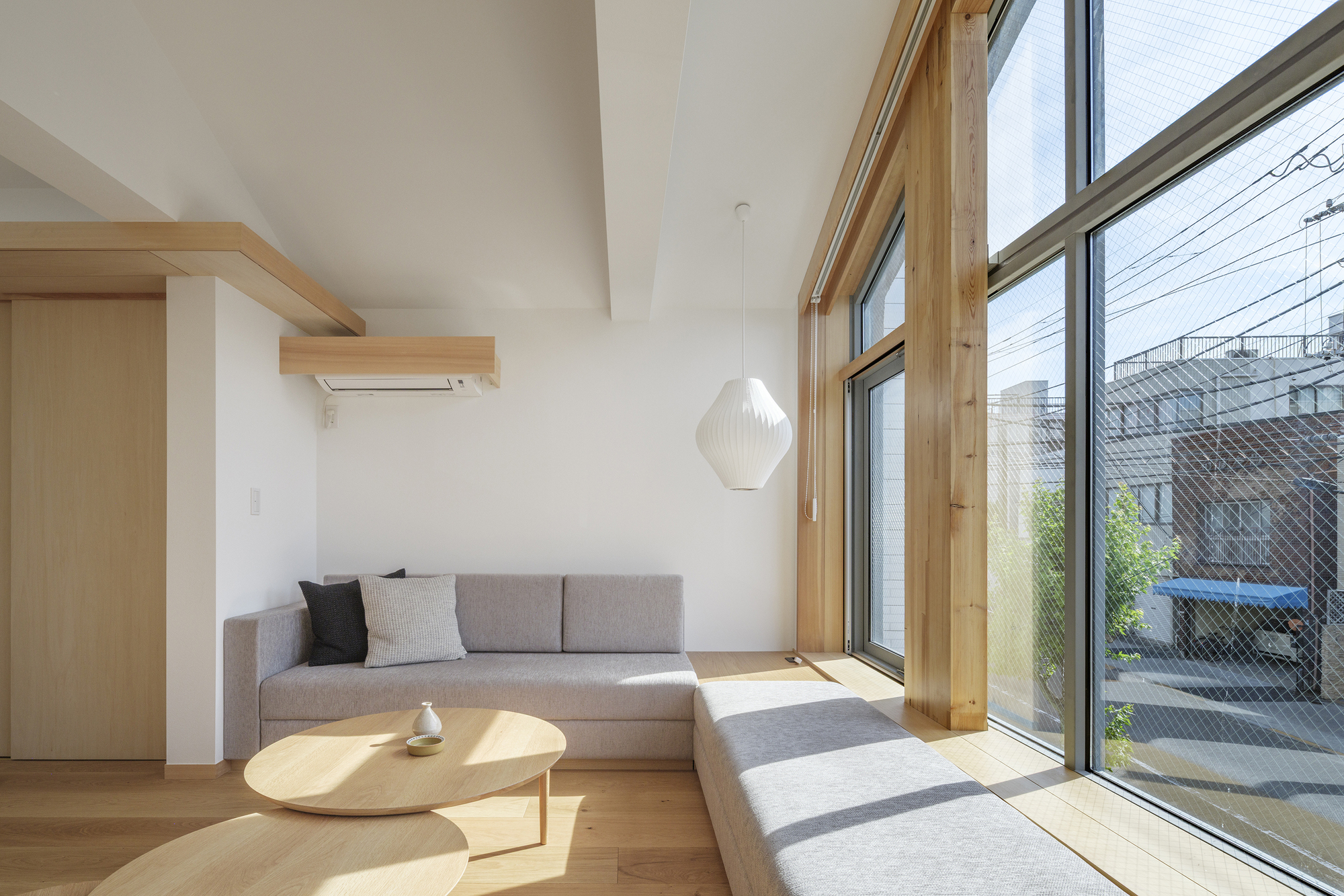 Living space with timber window frames casting afternoon sunlight across the floor and upholstered seating