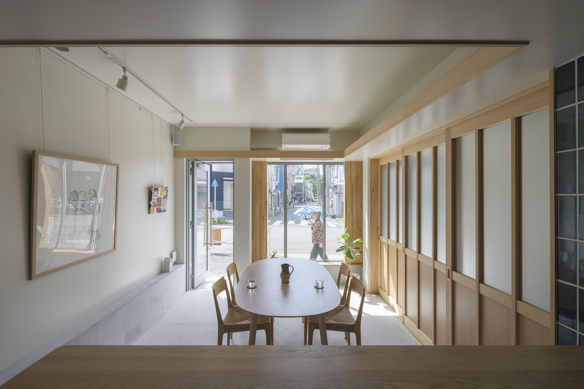 Interior dining area with timber screen partition and street-facing window framing a tree outside