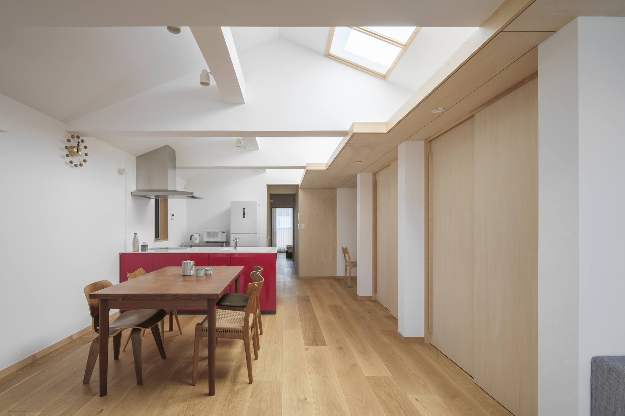 Dining area with timber partition wall and skylight overhead illuminating the oak flooring