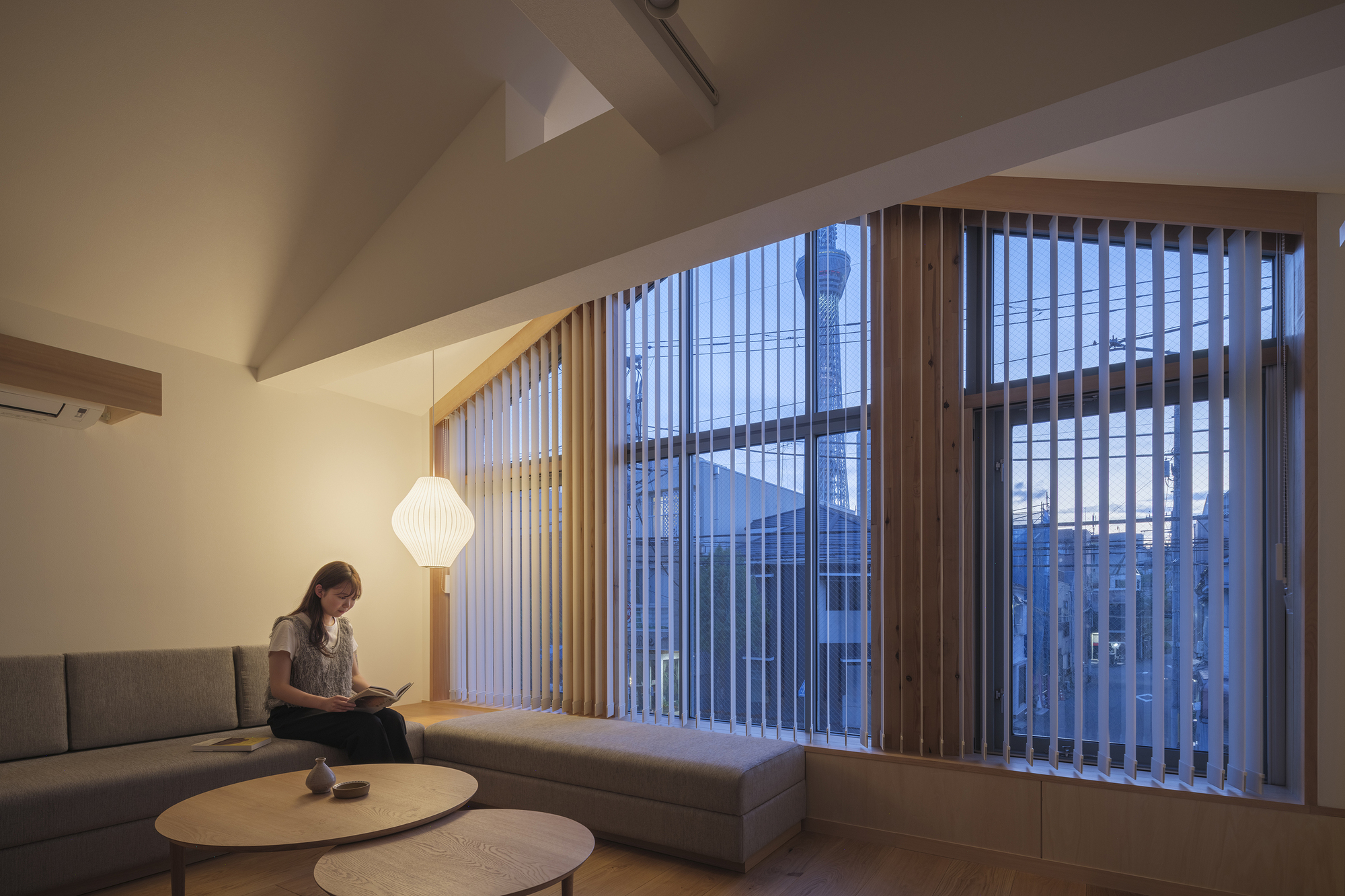 Interior seating area with vertical wooden screen windows facing the neighborhood at dusk