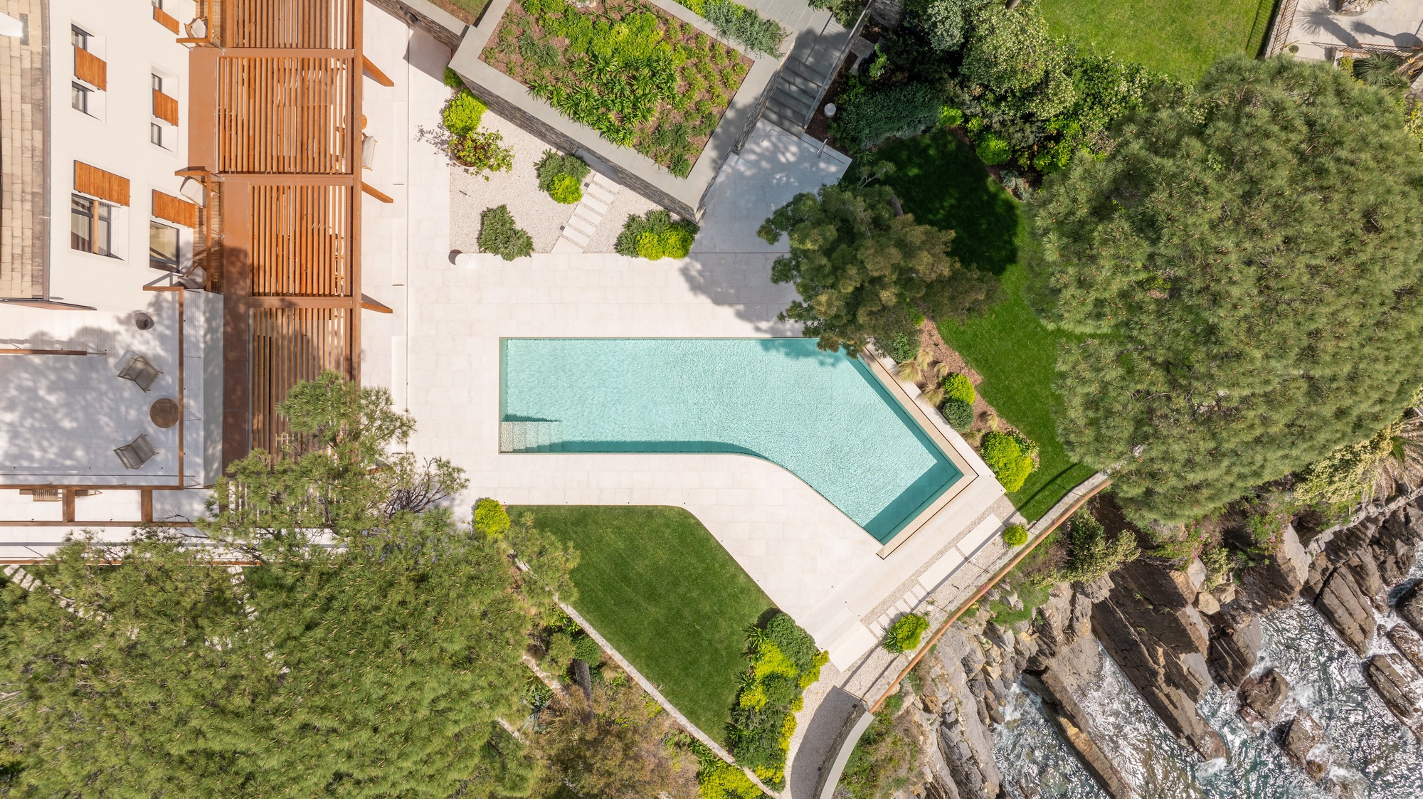 Aerial view of the angled pool deck and lawn bordered by rocky coastline