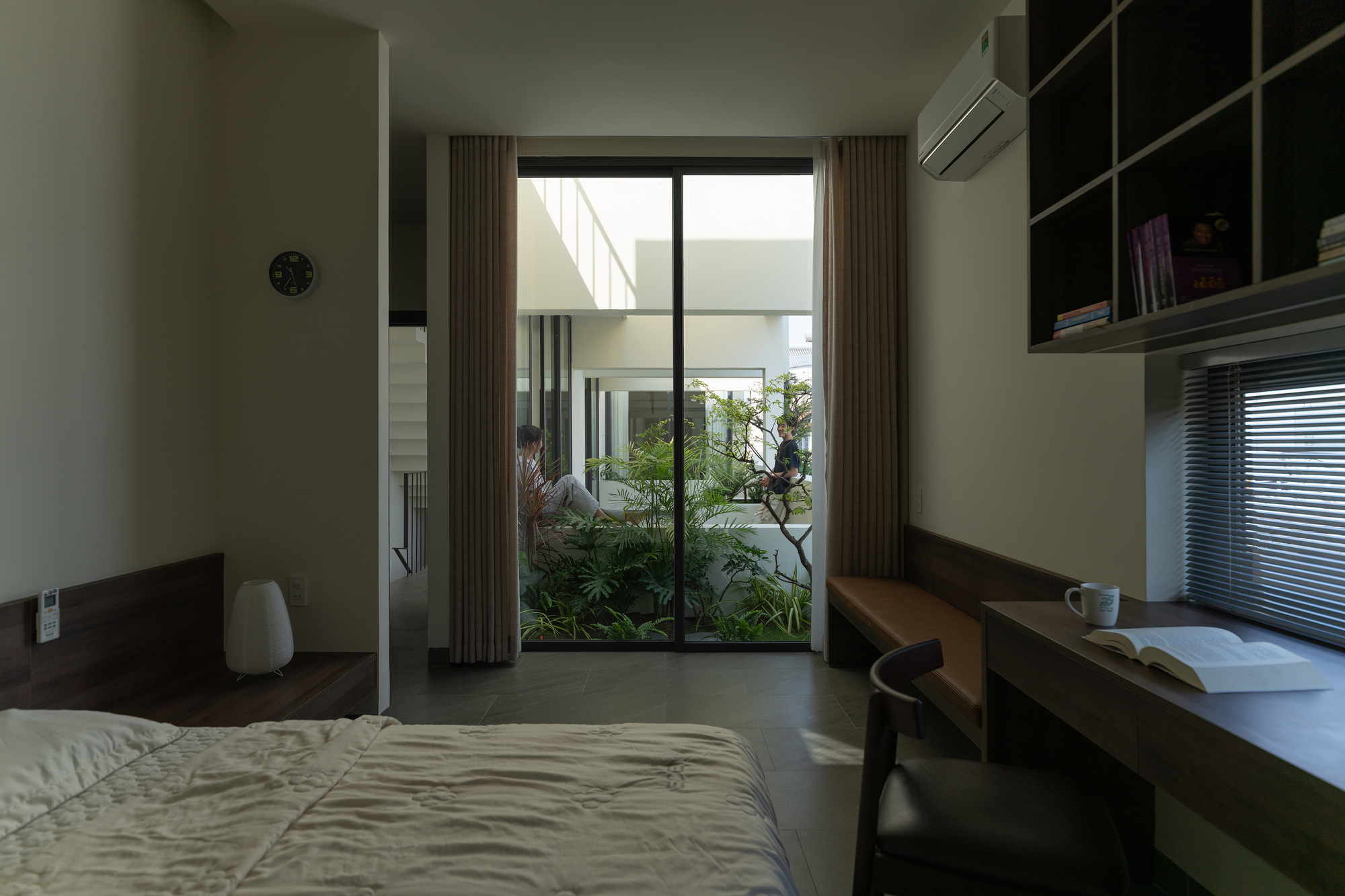 Bedroom with timber desk and glass doors opening to a small planted courtyard
