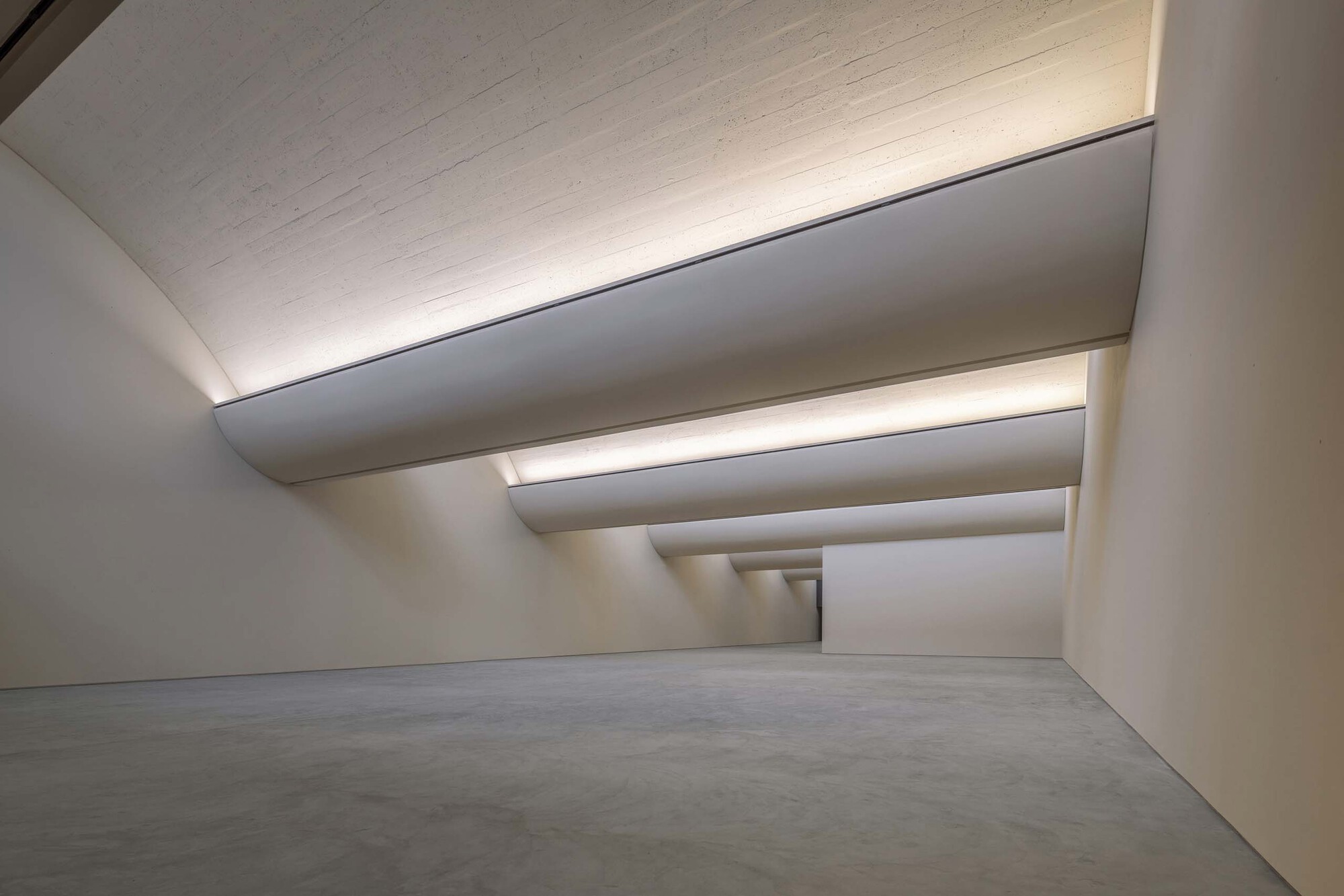 Interior gallery space with stepped ceiling coffers and recessed lighting over polished concrete floor