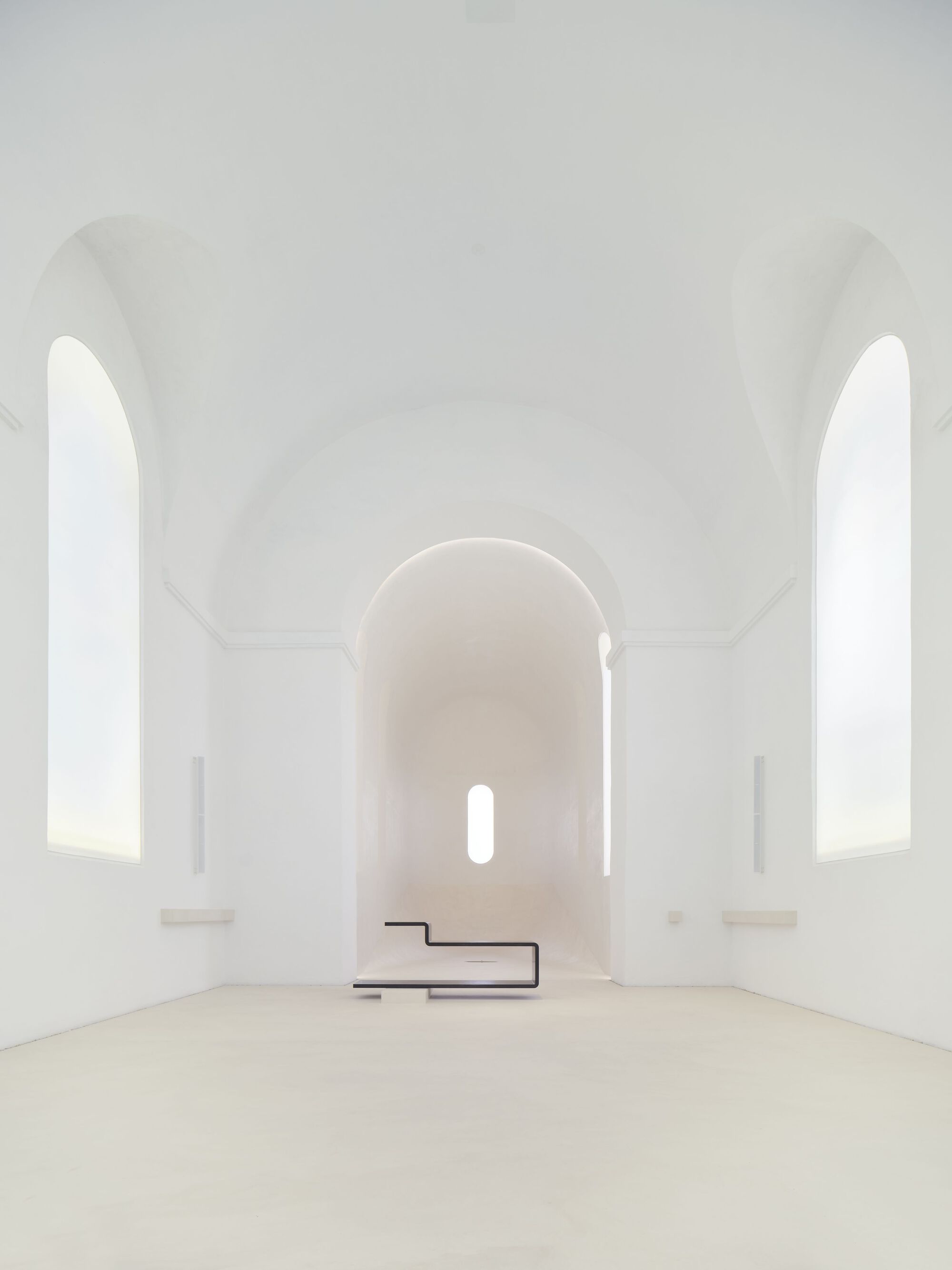 View toward the altar with cantilevered black steel platform beneath rounded apse window