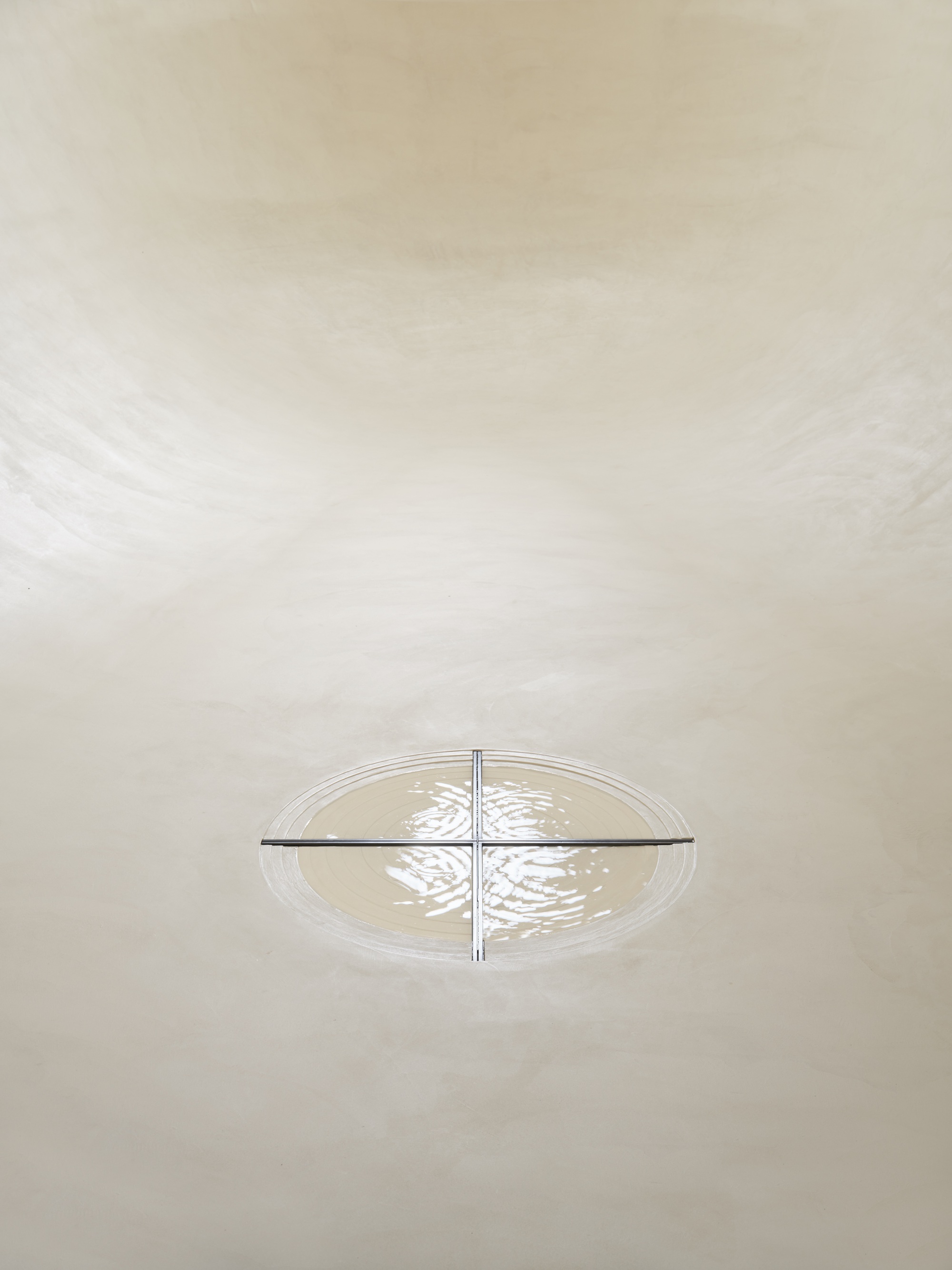 Overhead view of cruciform light fixture casting patterned shadows on curved white plaster vault