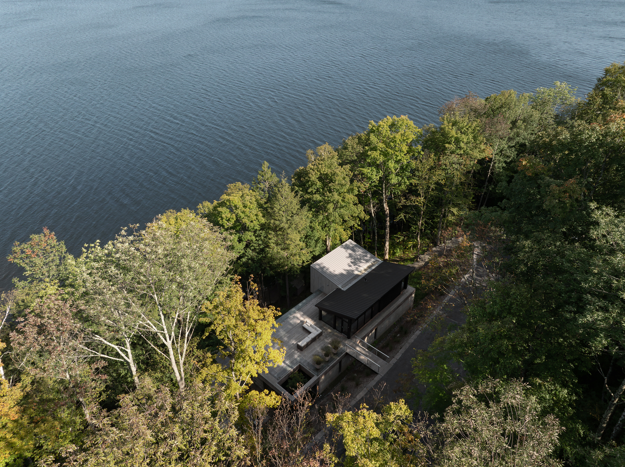 Aerial view of the lakeside residence nestled among trees on a sloped wooded lot