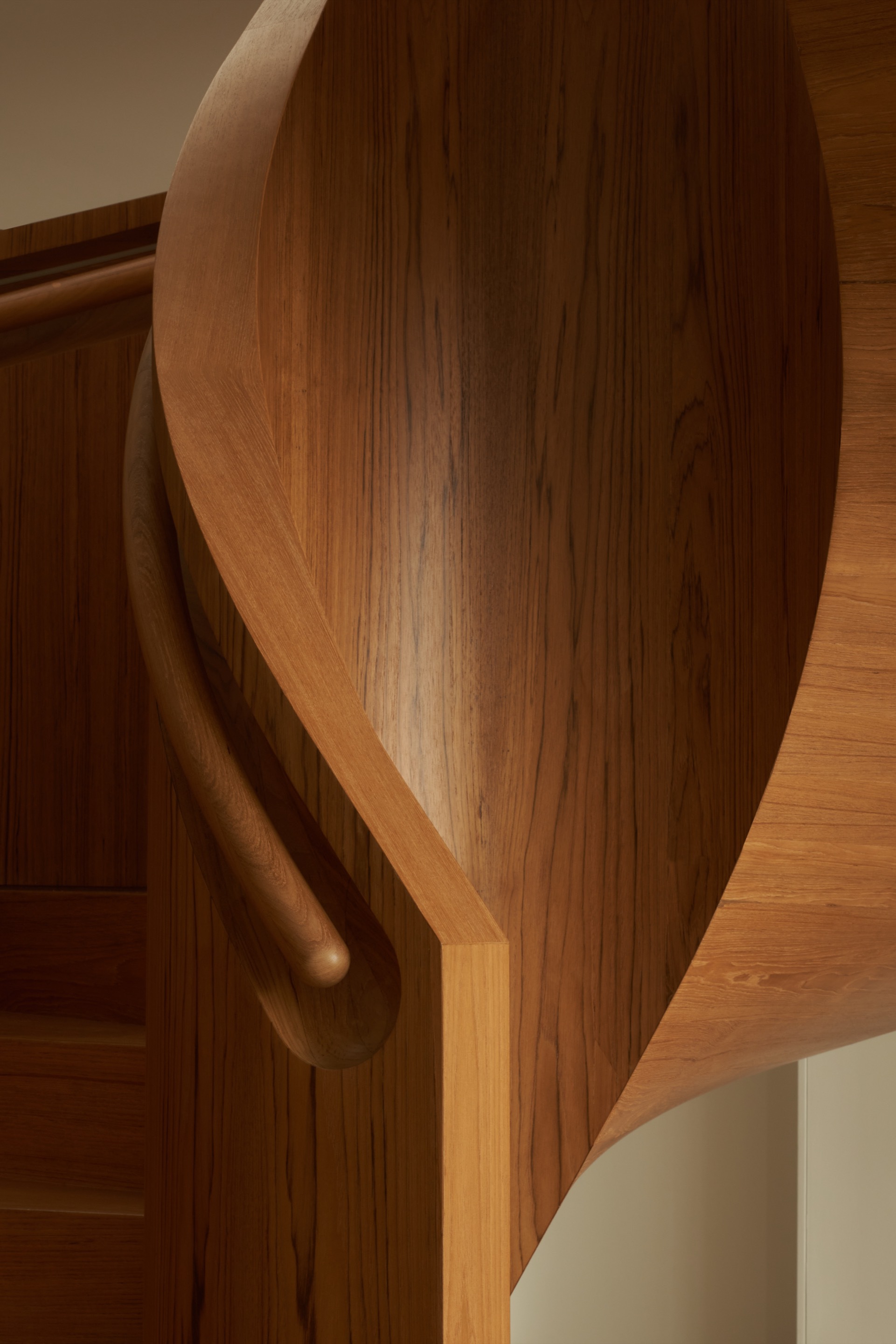 Close-up of the curved timber staircase with integrated handrail in warm afternoon light