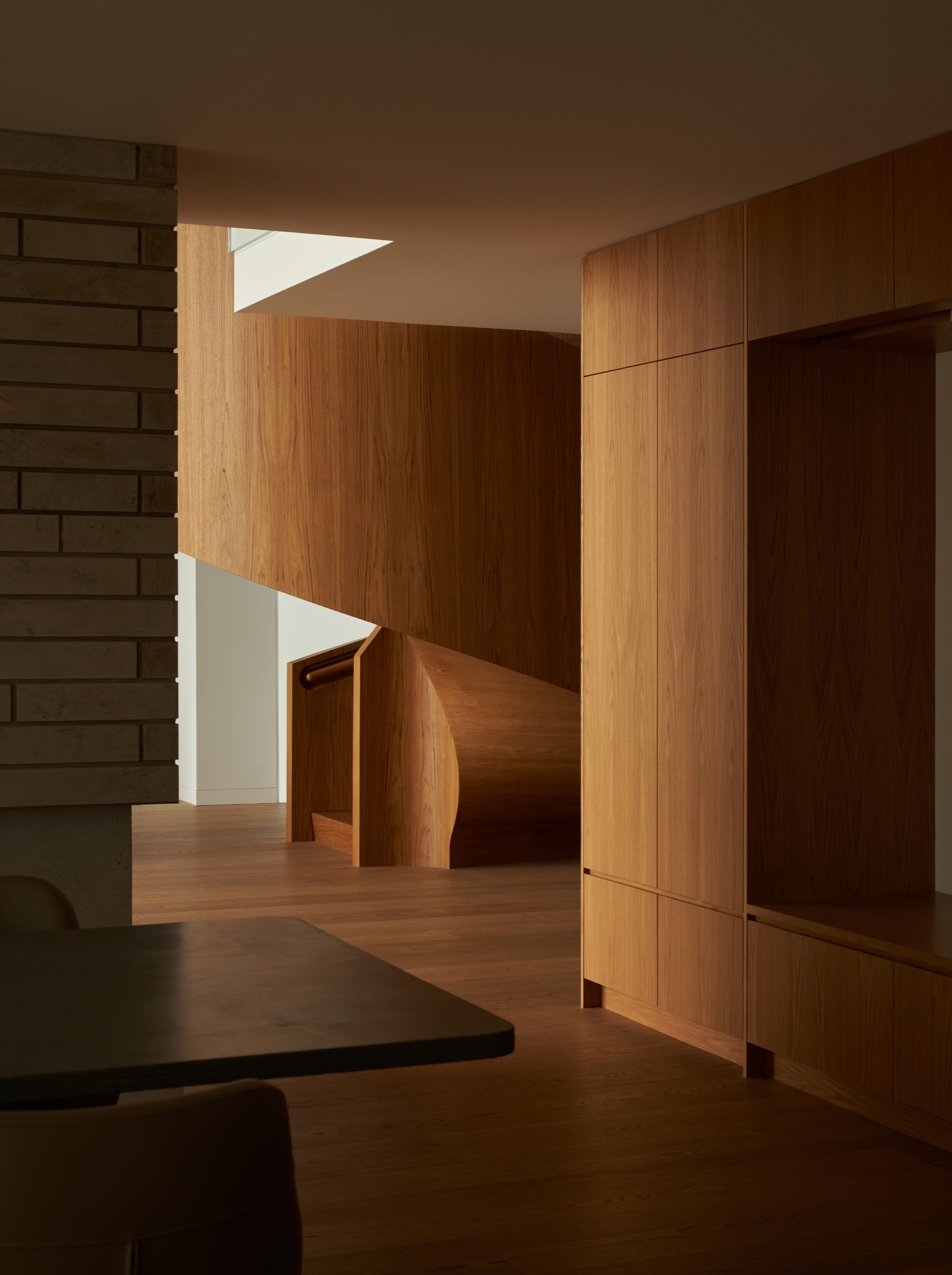 Interior view showing timber-clad walls and curved staircase with skylight above