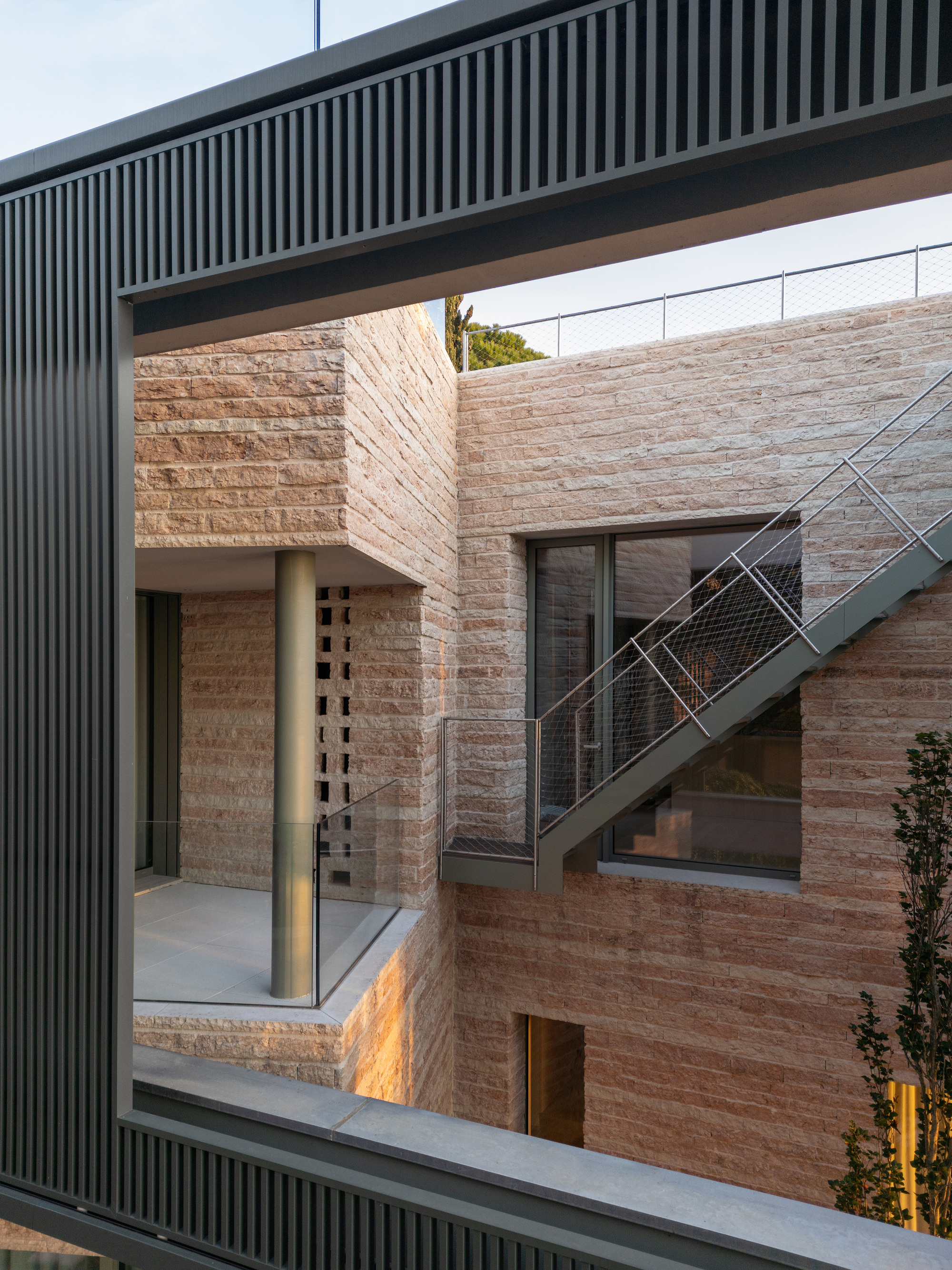 Courtyard view showing rammed earth walls, external metal stair and overhanging slatted soffit