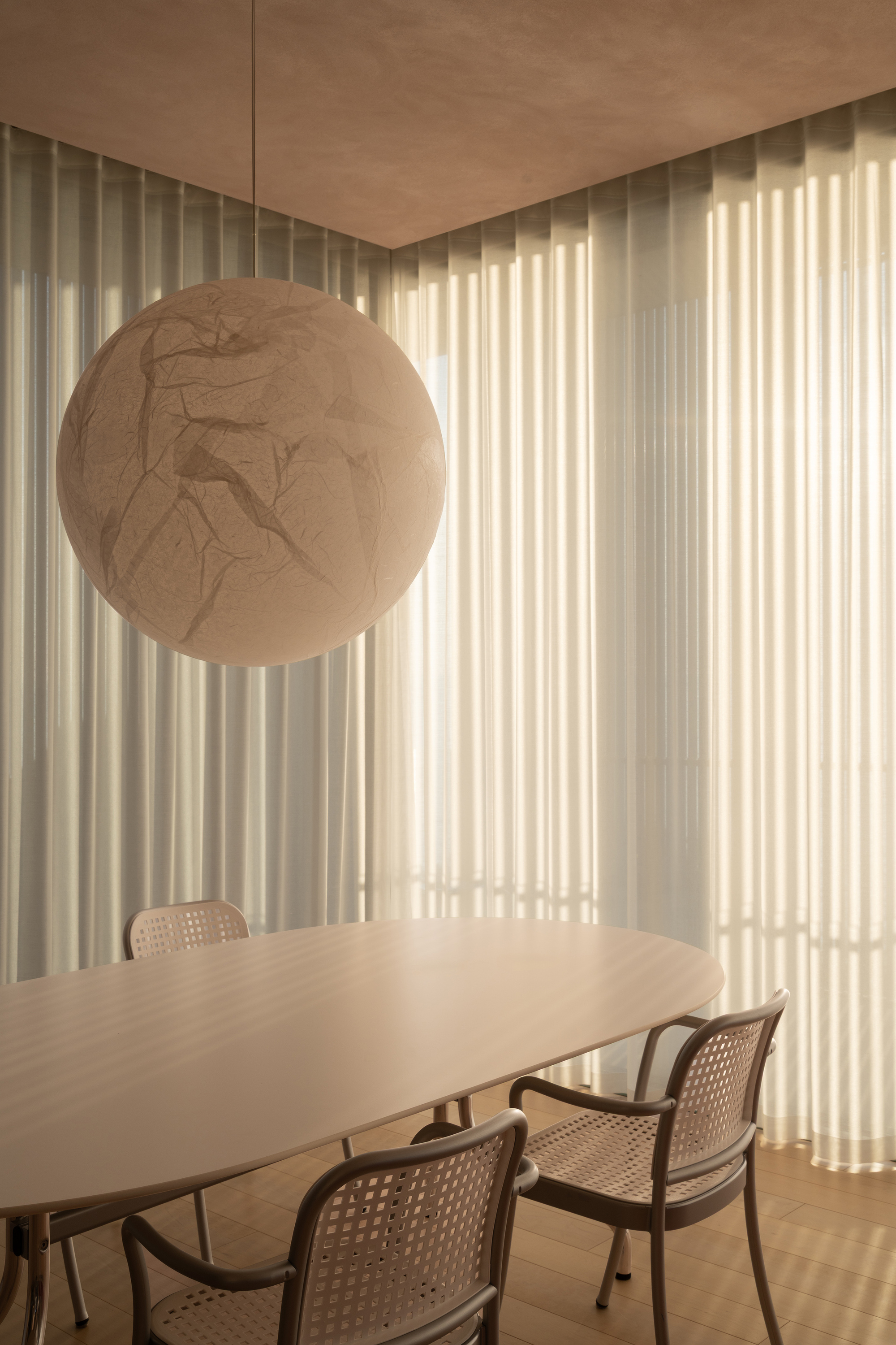 Dining area with spherical pendant light and sheer curtains filtering soft afternoon light