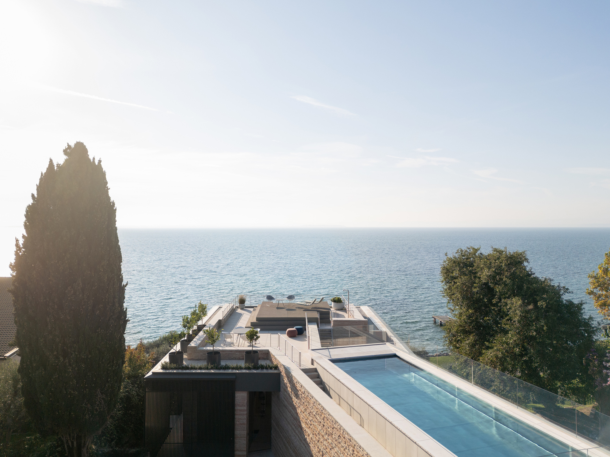 Aerial view of the rooftop terrace with pool and glass-edged parapet facing the waterfront at dusk