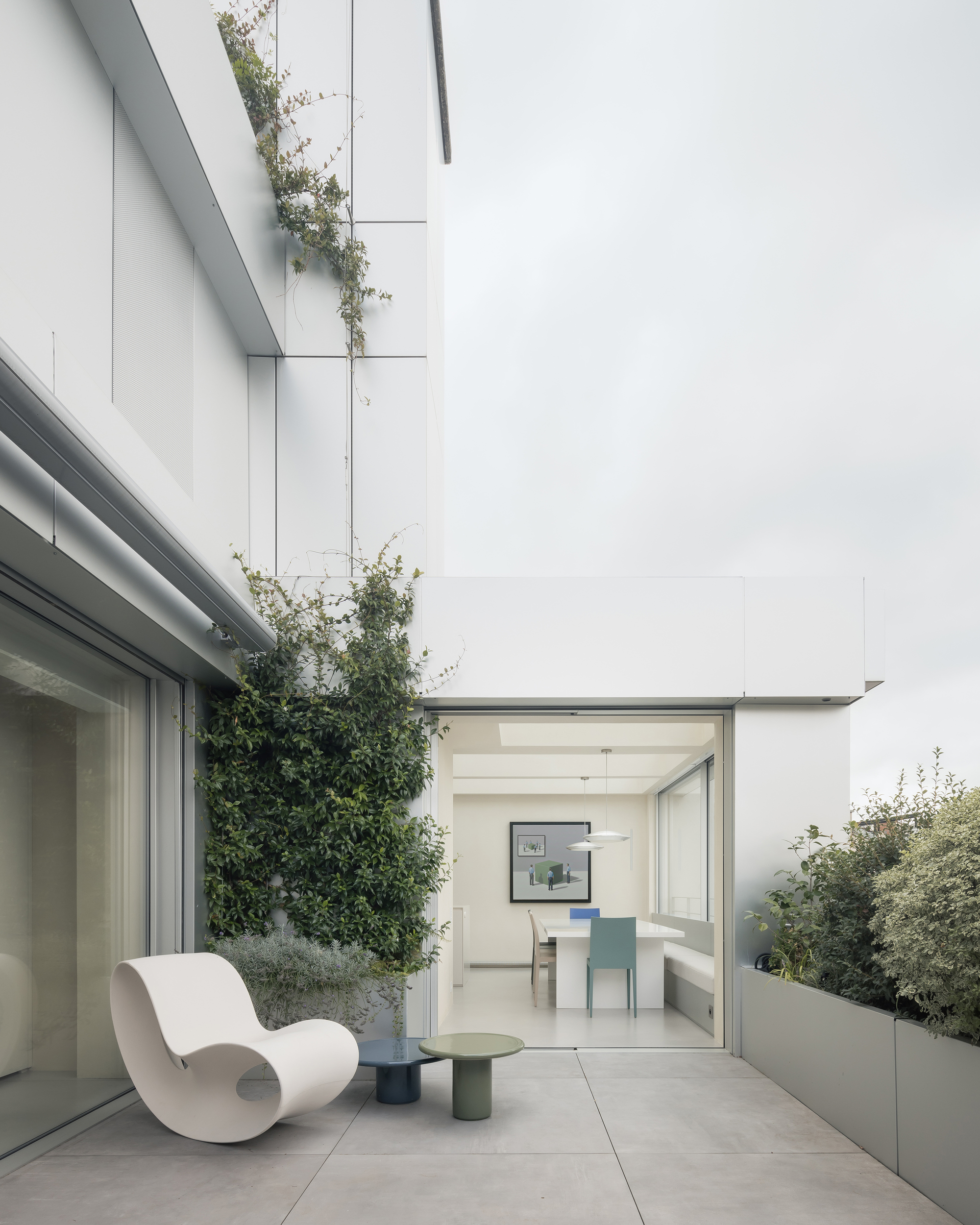 Terrace with planted beds and single chair looking through glazed doors toward the interior