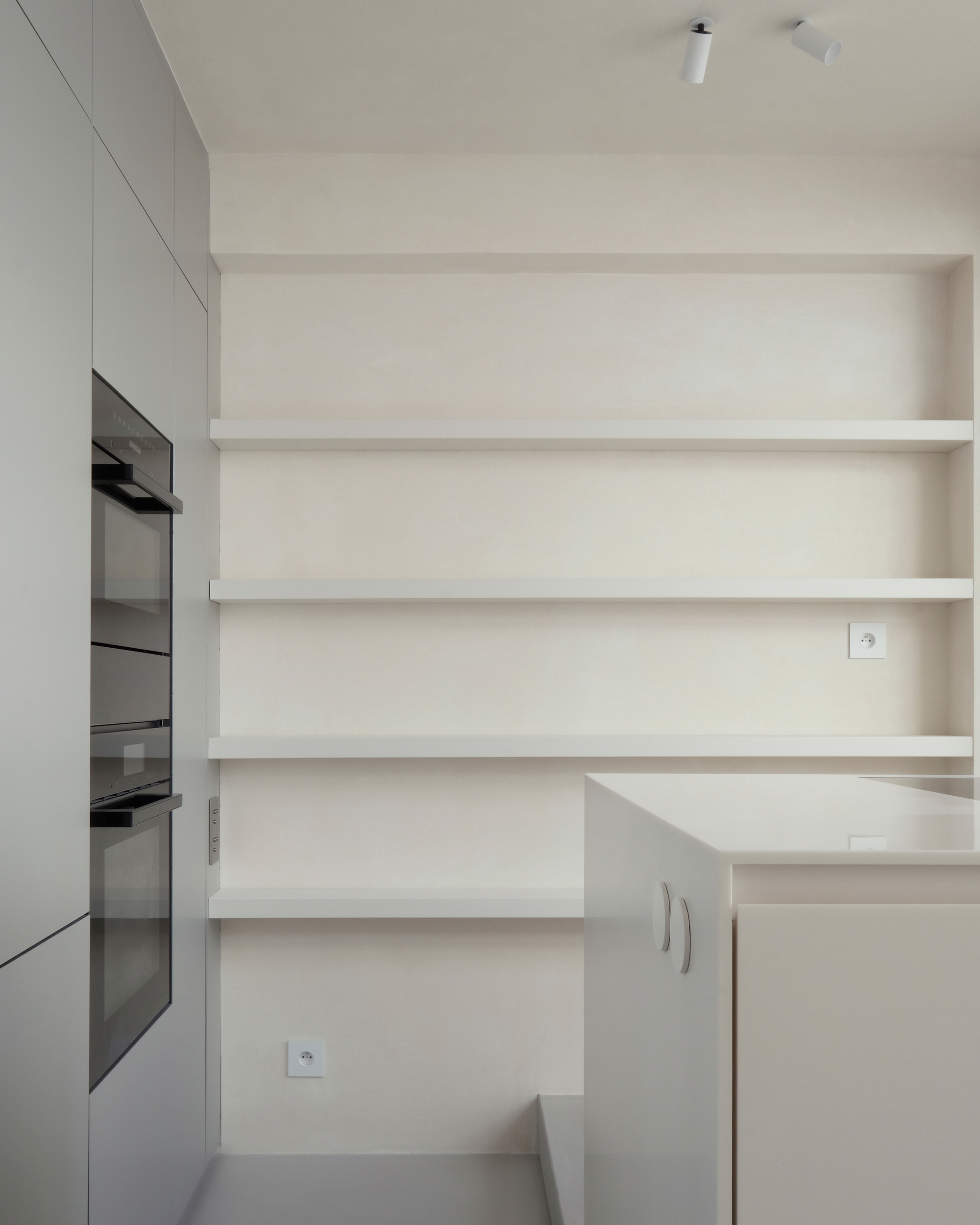Kitchen wall with horizontal floating shelves above integrated oven cabinets