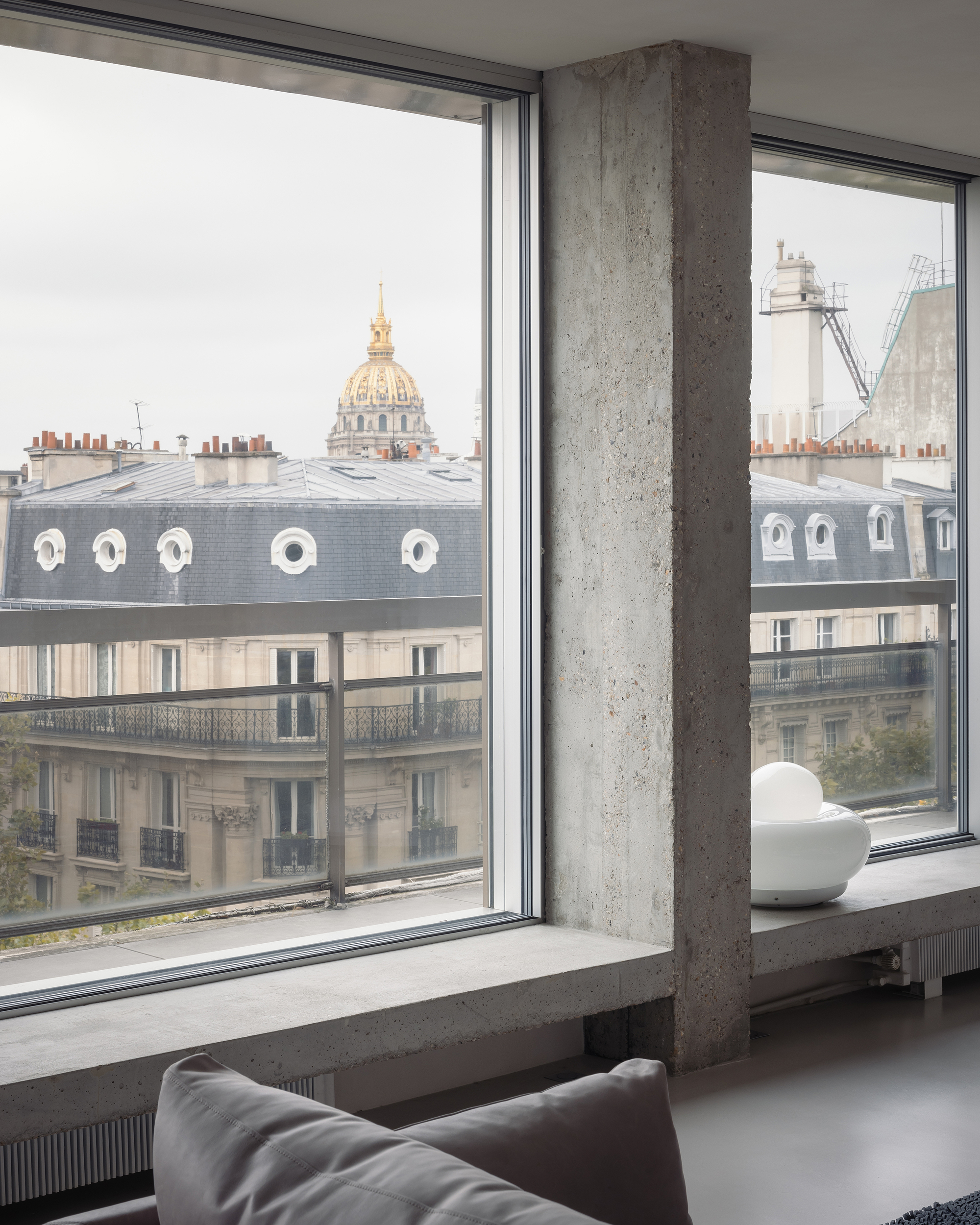Exposed concrete column at corner window overlooking mansard roofs and gilded dome