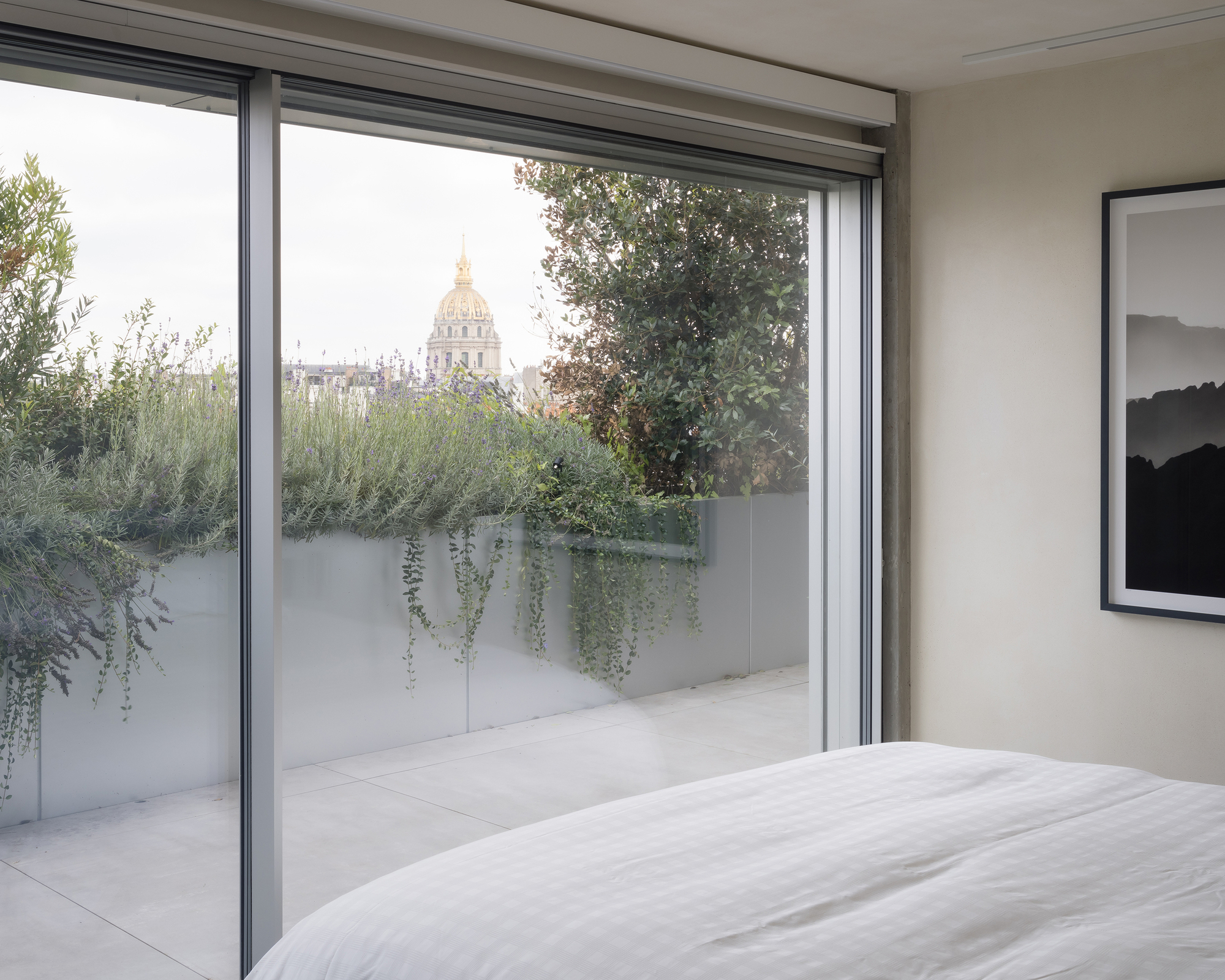 Bedroom with sliding glass door opening to planted terrace with trailing vines