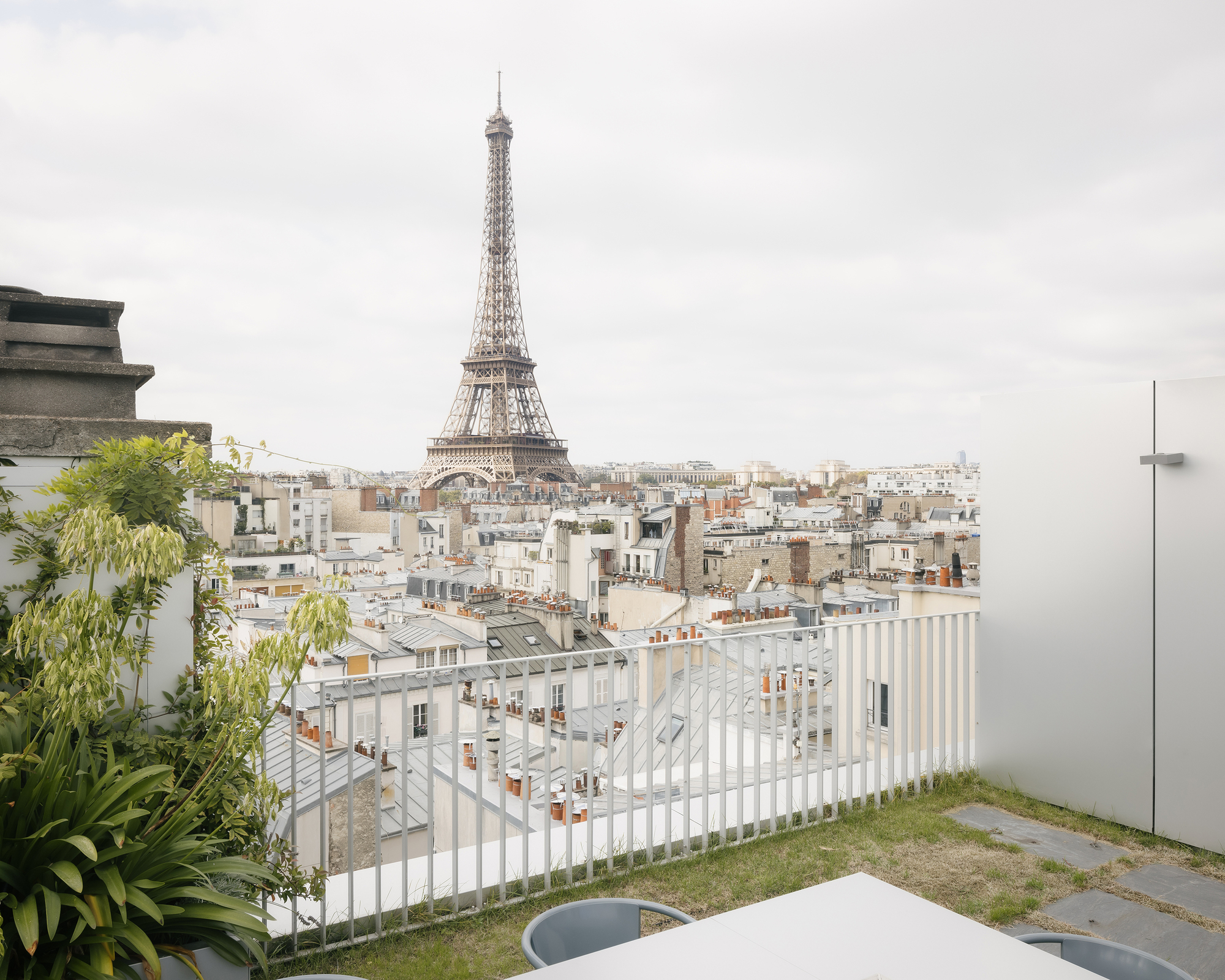 Rooftop terrace with white vertical slat railing and lawn facing the historic cityscape in morning light