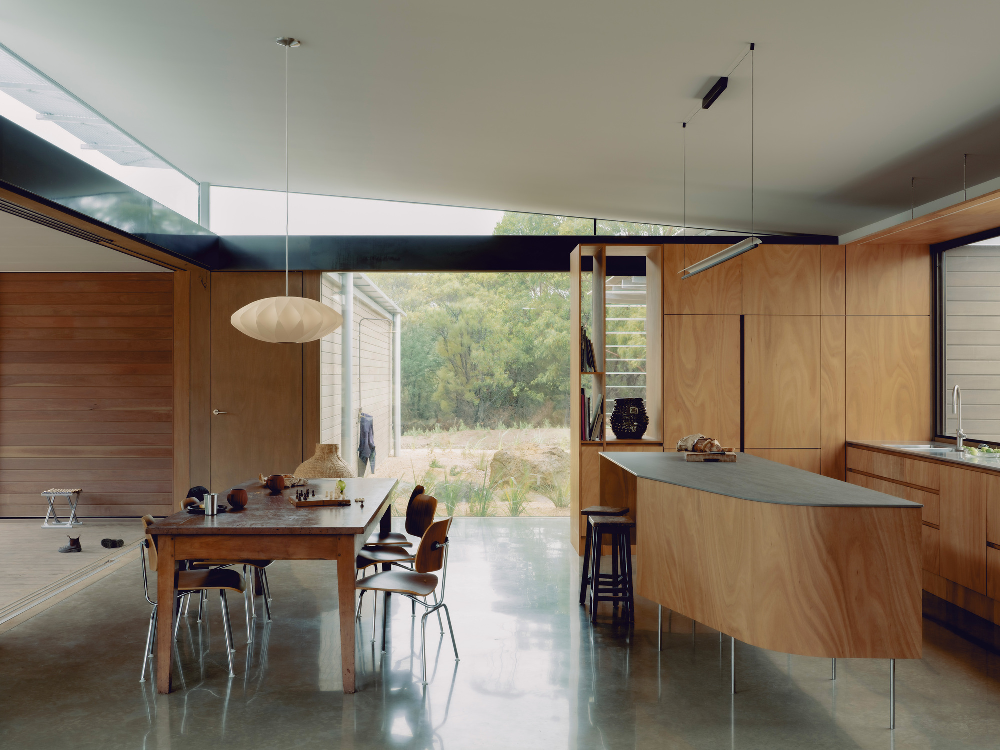 Open-plan kitchen and dining space with timber cabinetry beneath a horizontal clerestory window