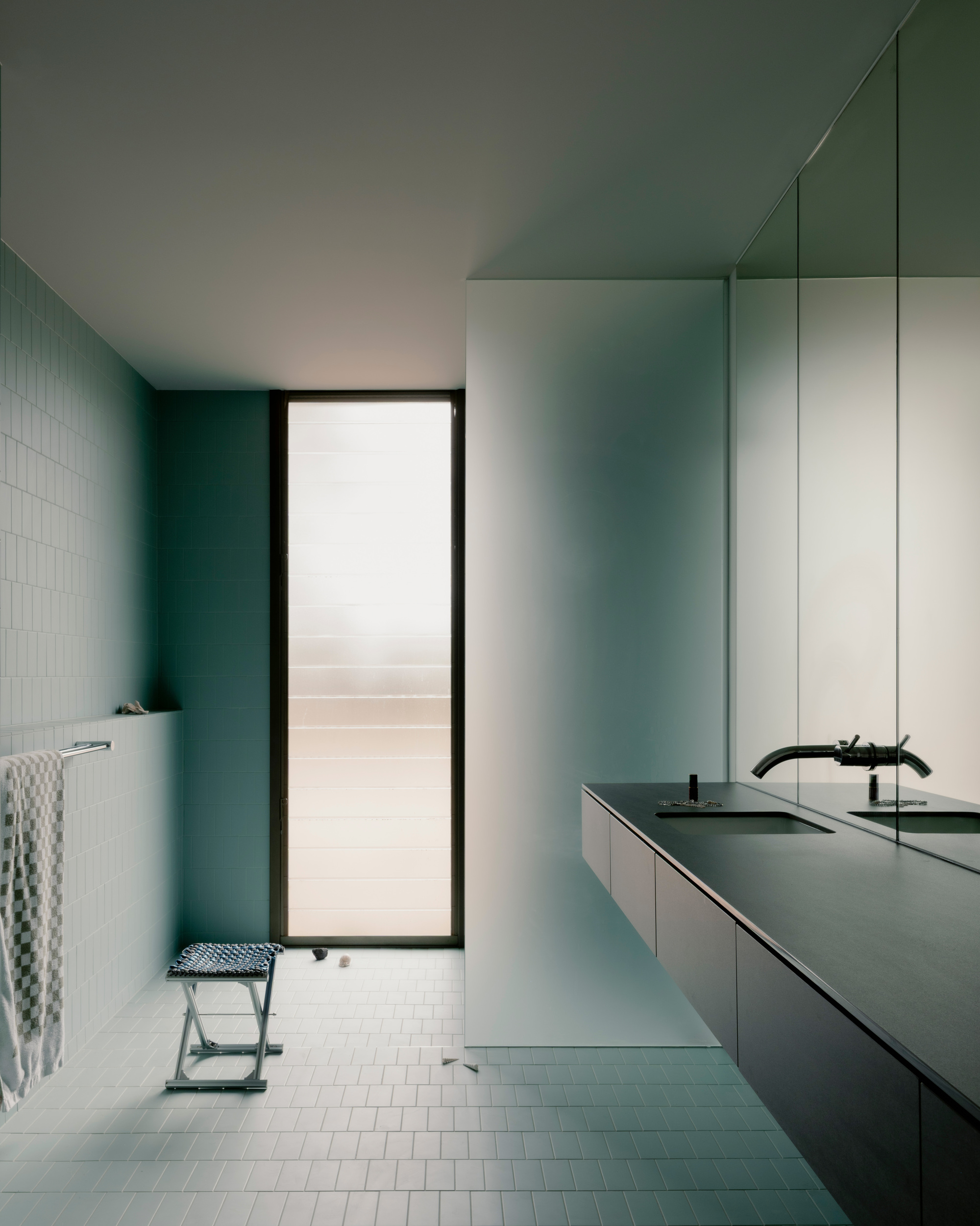 Bathroom vanity in pale blue with white subway tiles and mirrored wall beside a doorway