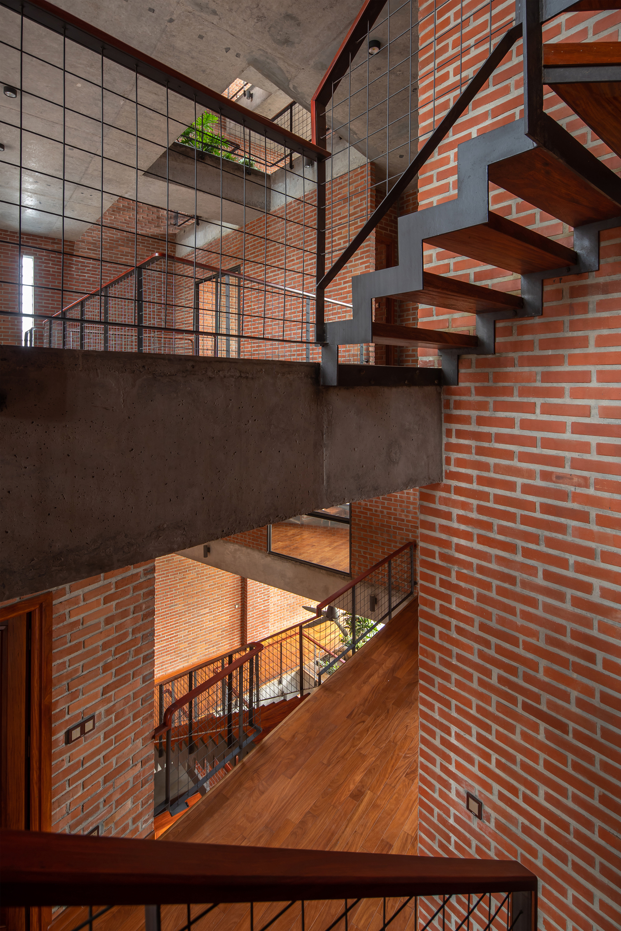 Vertical view through stacked levels showing cantilevered concrete slabs, floating timber stairs, and brick walls