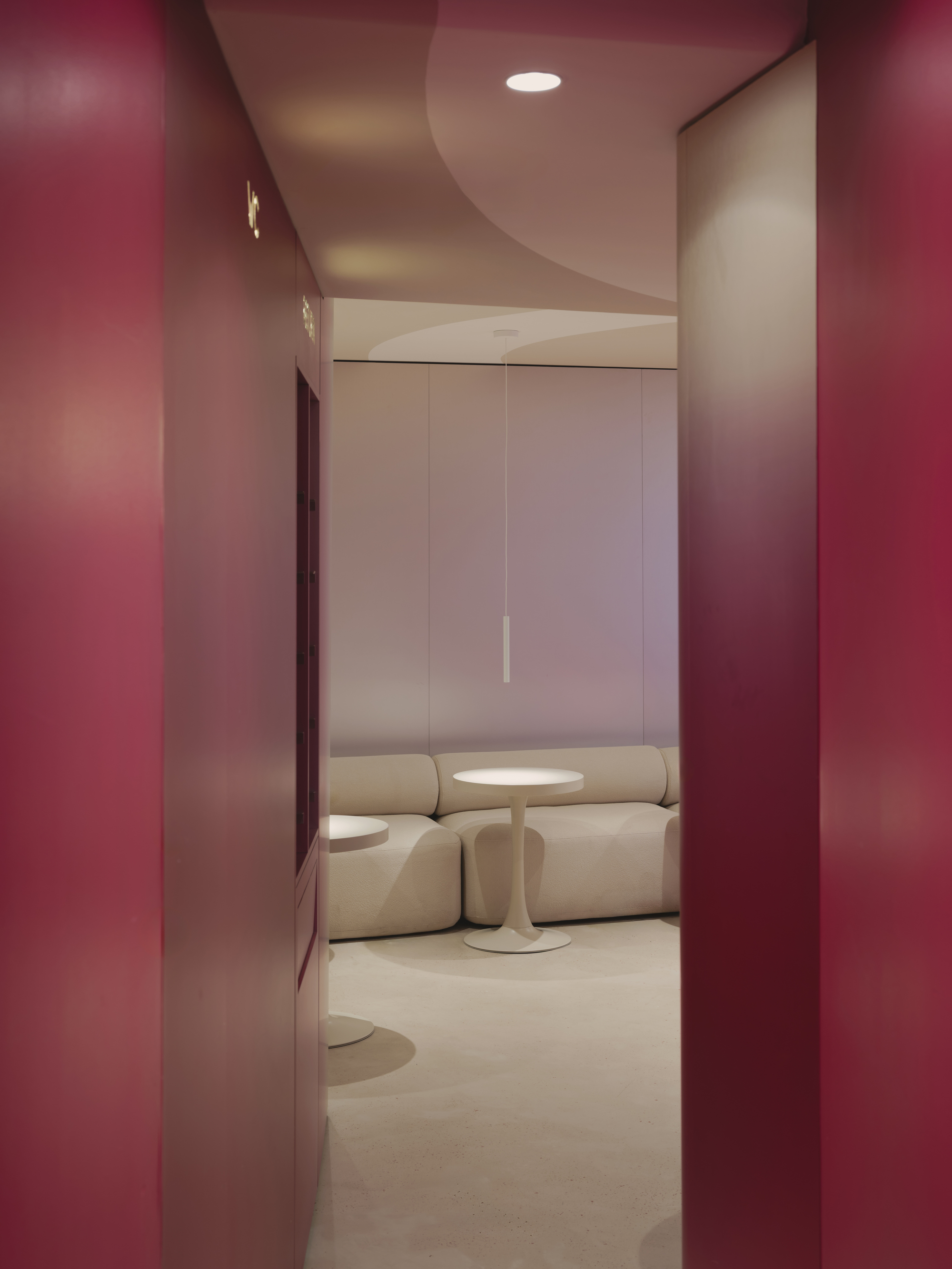 View through burgundy doorway into seating area with cloud-shaped ceiling feature overhead