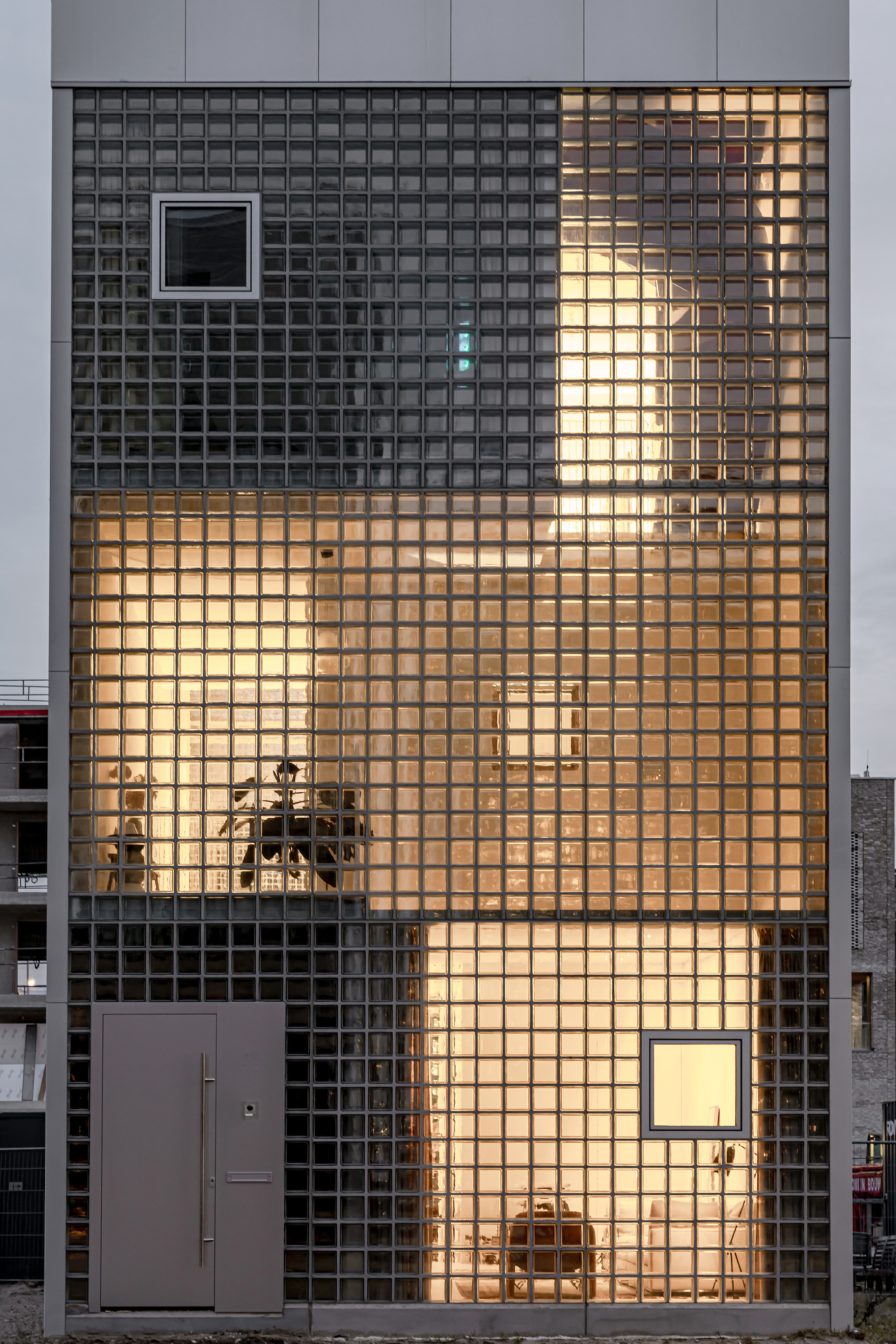 Front elevation of glass block wall with stacked framed openings and interior lighting visible