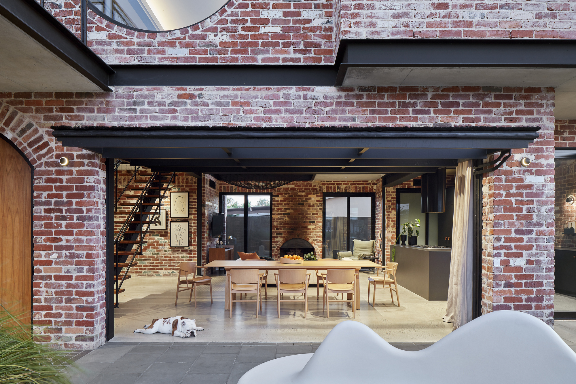 View through brick arches into the dining room with exposed steel beams and polished concrete floor
