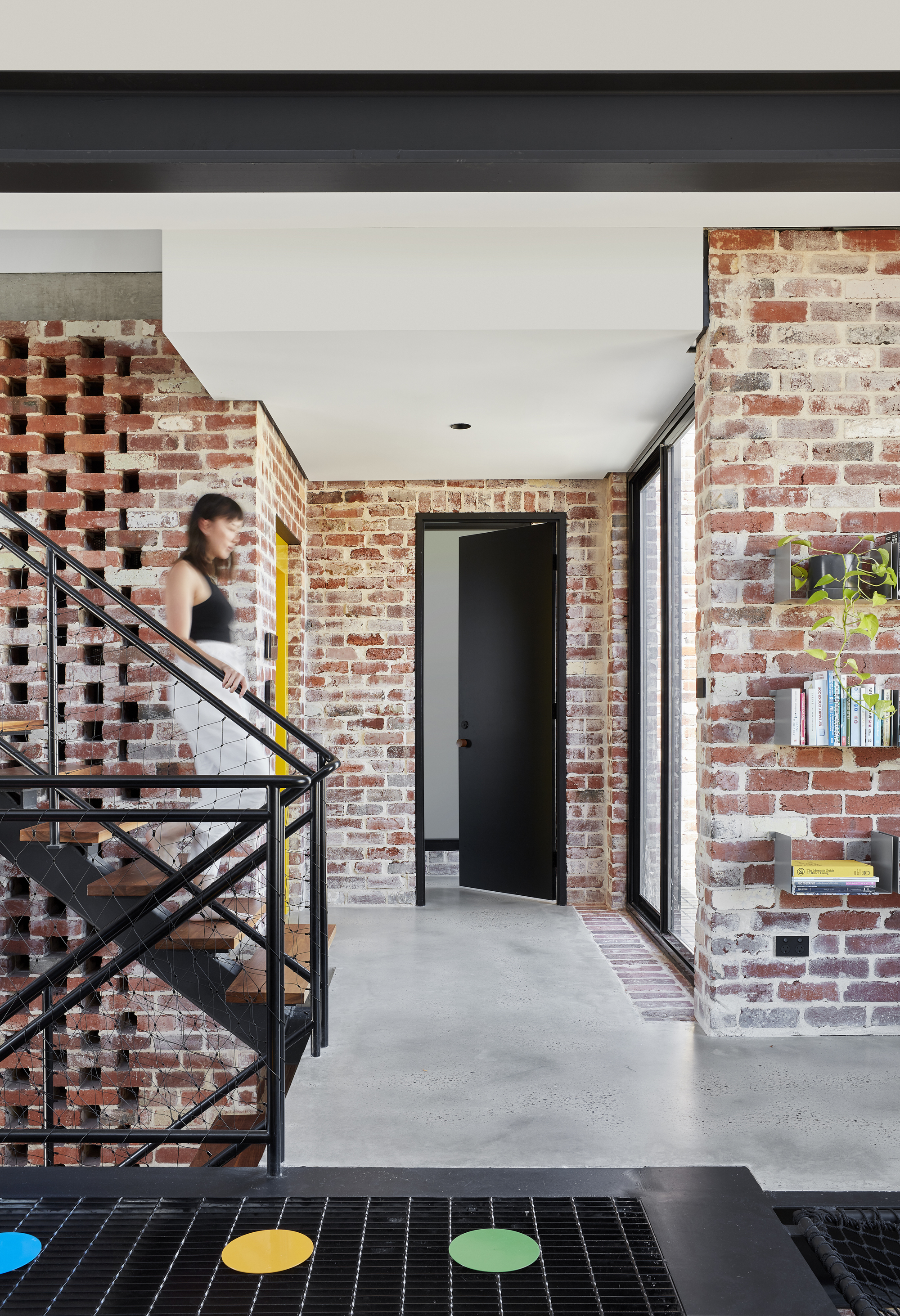 Corridor with perforated brick screen beside the steel staircase and a person descending in motion blur