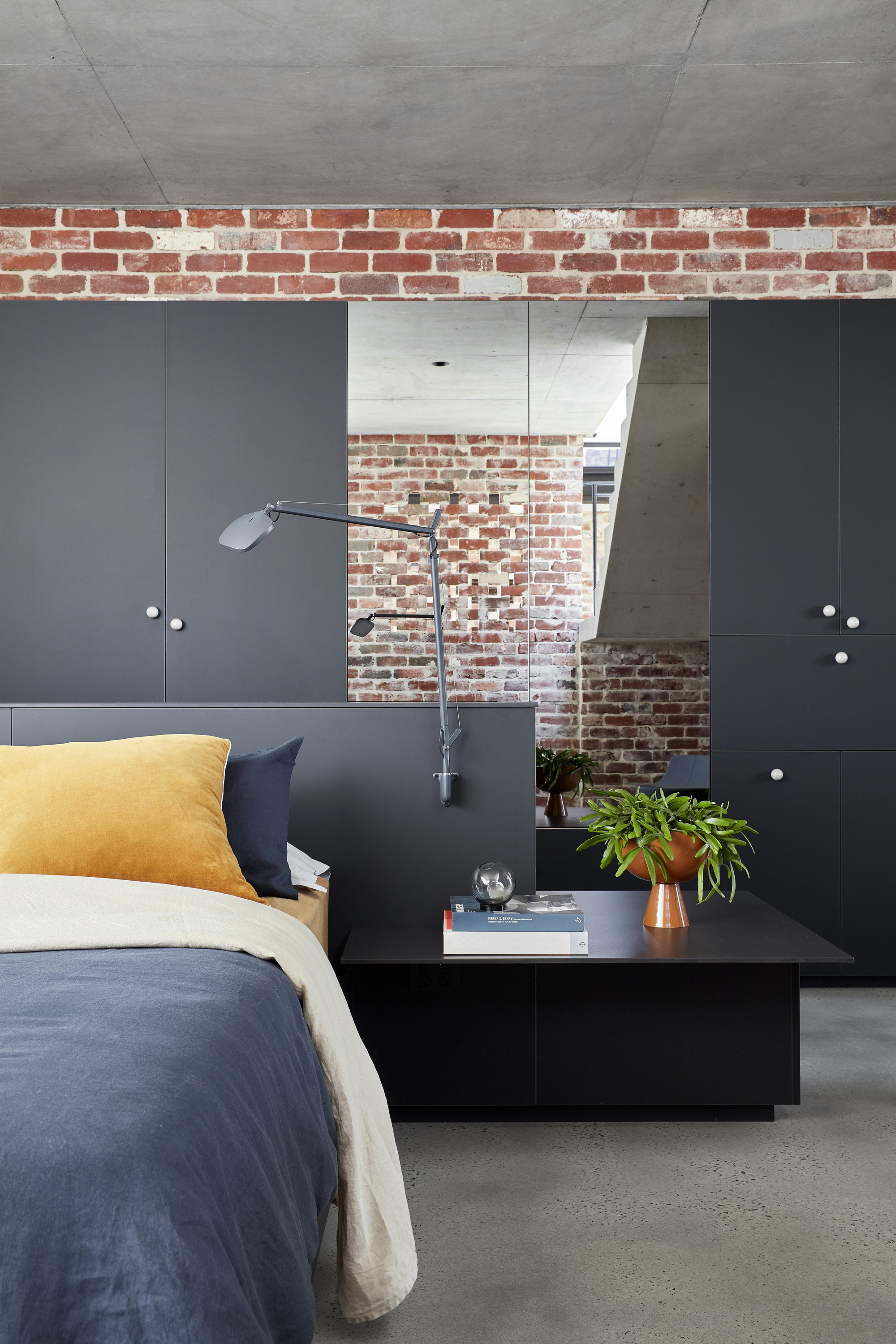 Bedroom with black built-in cabinetry and exposed brick wall visible through doorway opening