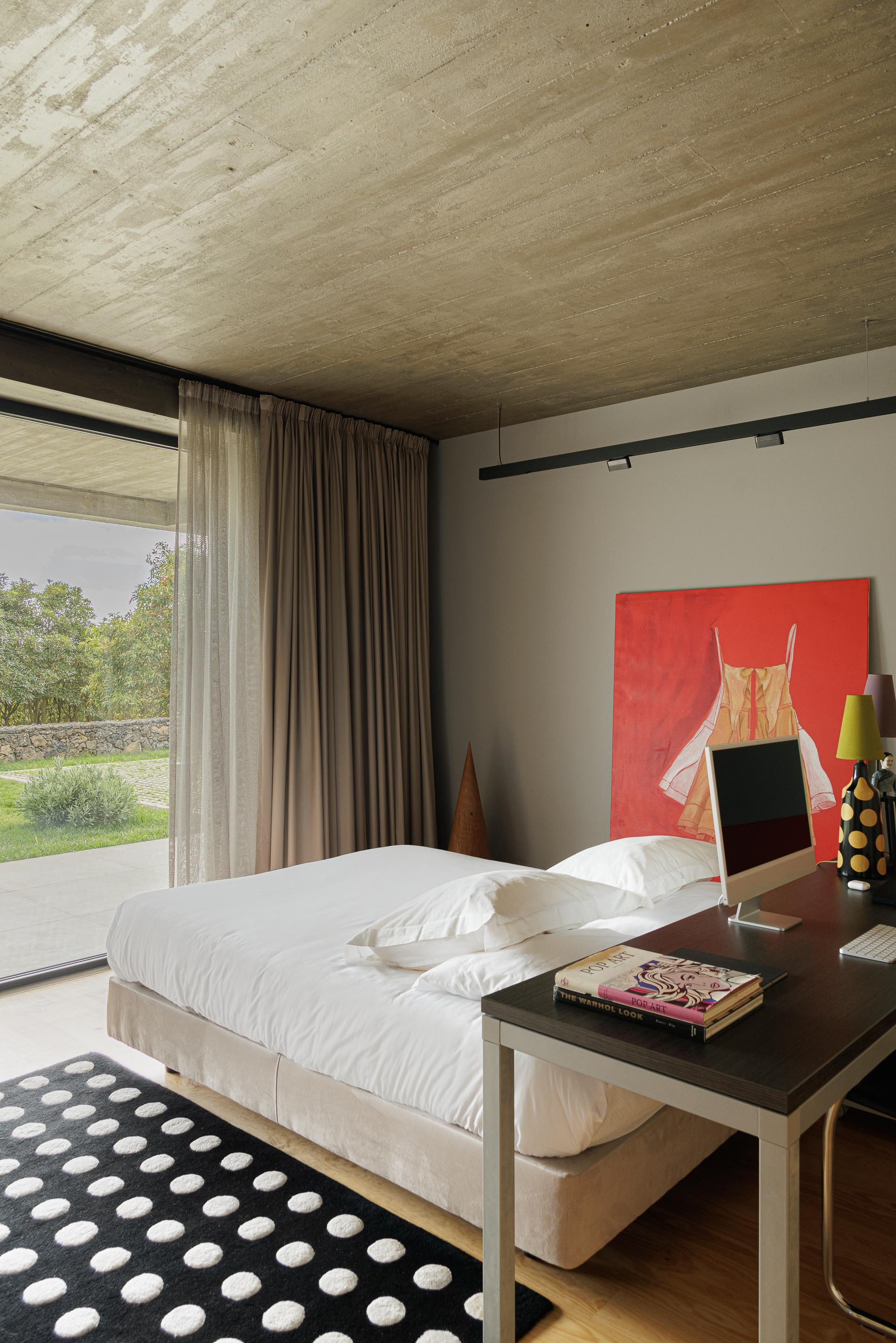 Bedroom with exposed timber ceiling, full-height glazing with sheer curtains and view to garden