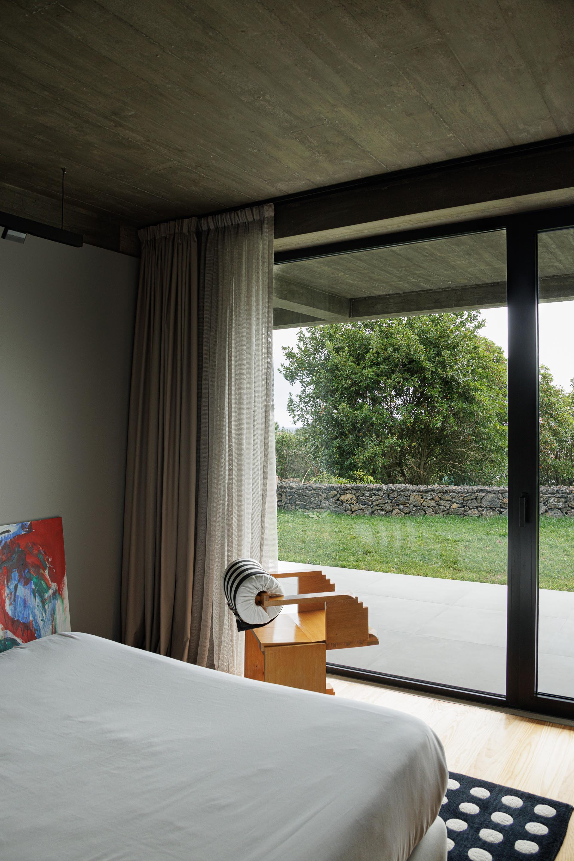 Floor-to-ceiling window framing a stone wall and garden beyond a bedroom